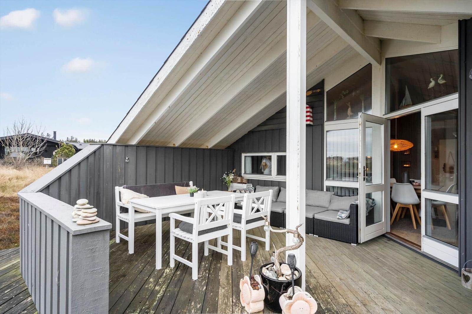 Deck with table, chairs, and seating. Entrance to interior furnishings.