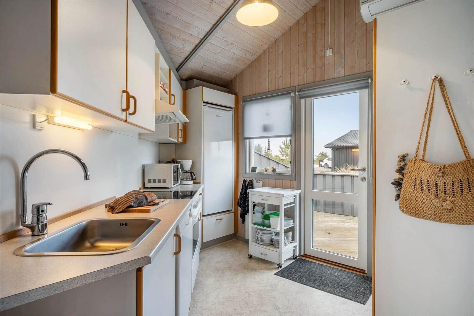 Kitchen with sink, refrigerator, and window to terrace.