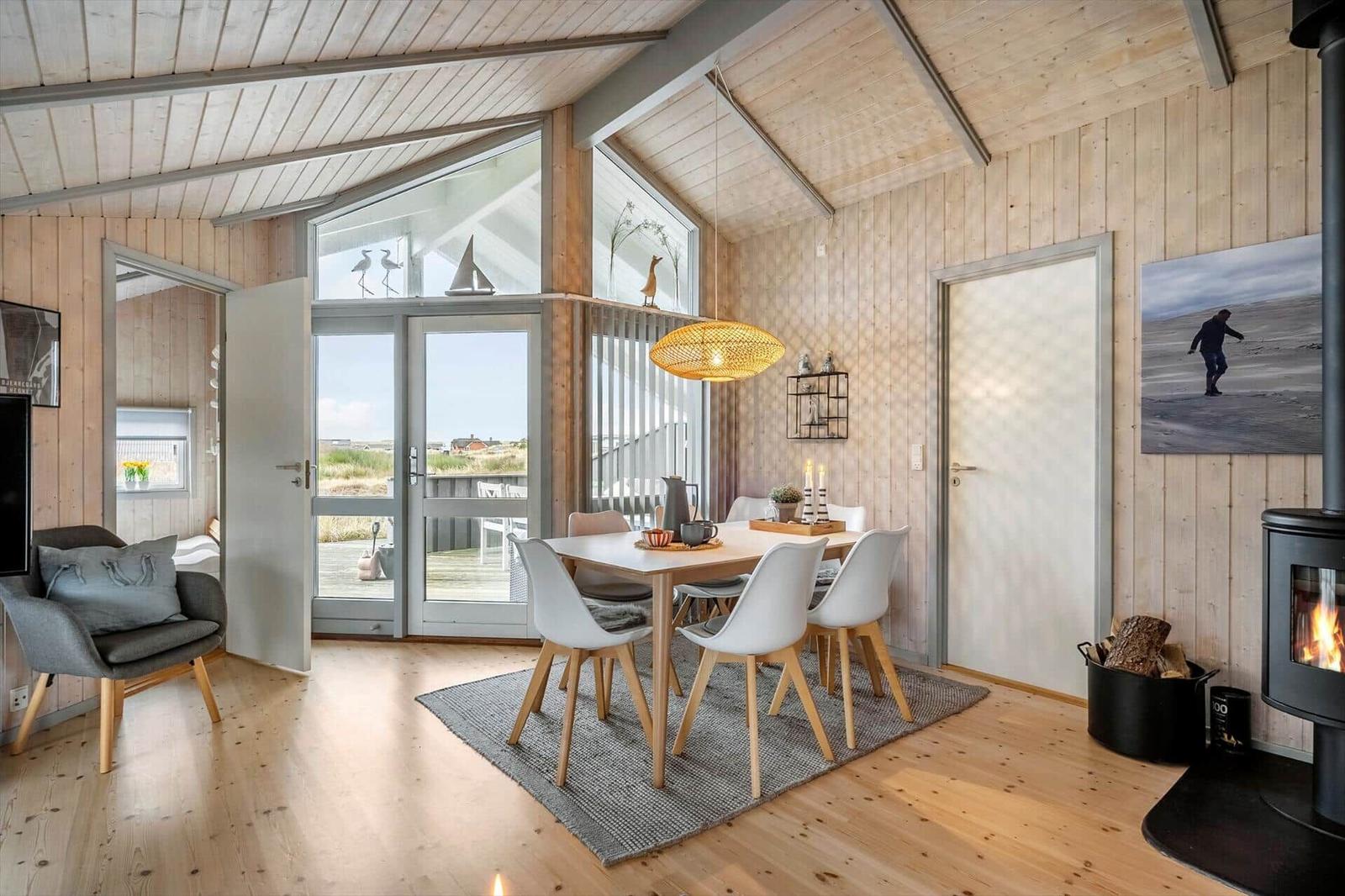 Dining room with table, chairs, and fireplace. Entrance to terrace with sea view.
