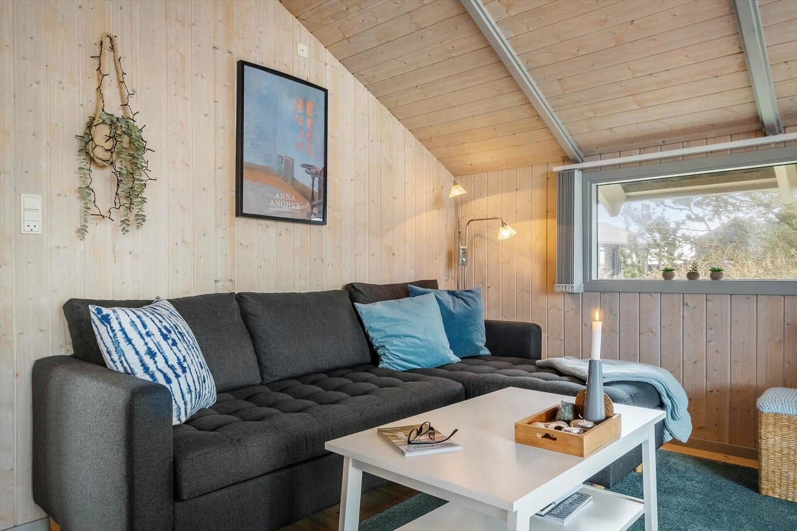 A living room with a gray sofa, white table, and wooden walls.