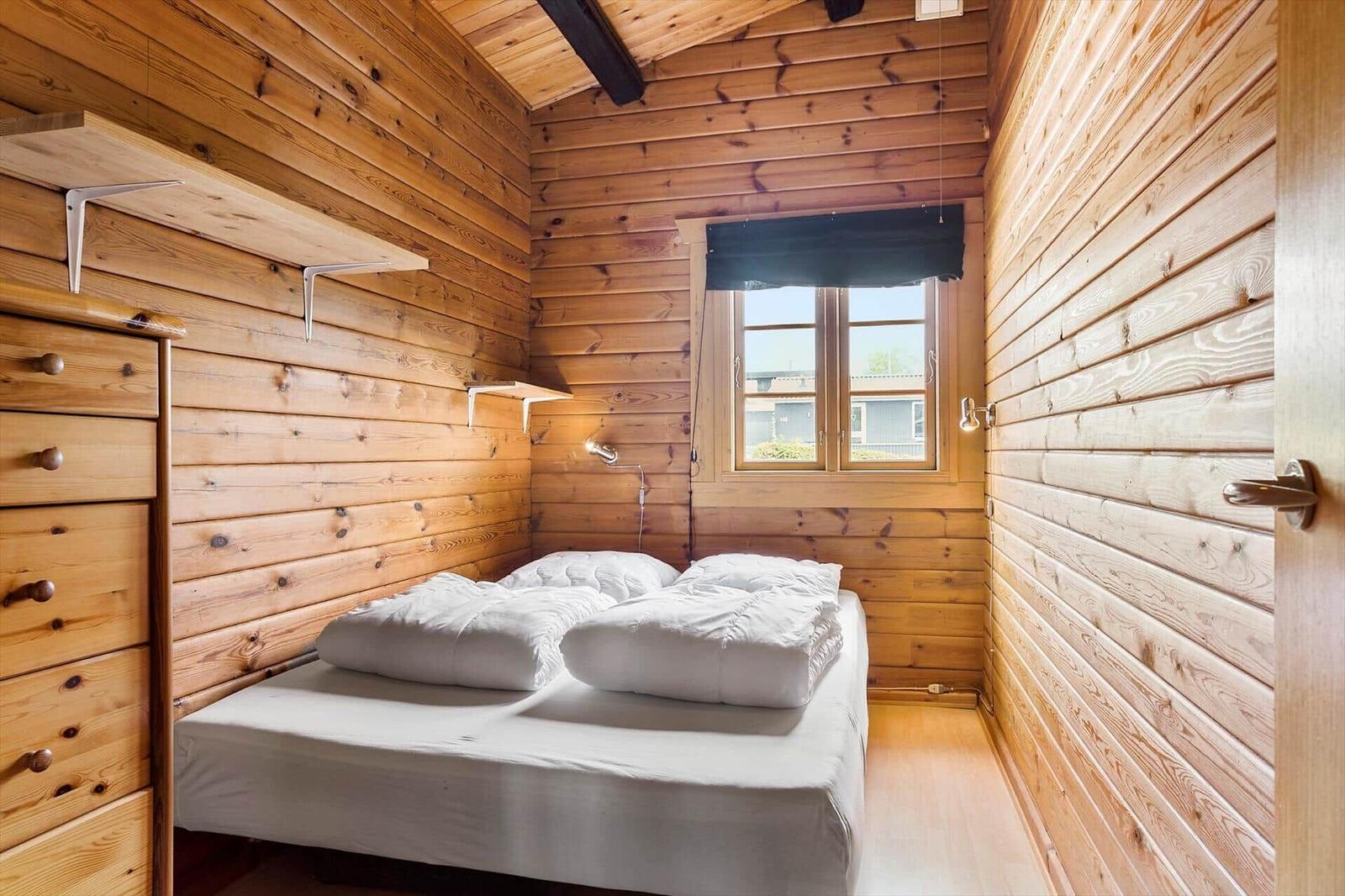 Bedroom with wooden walls, bed, and window