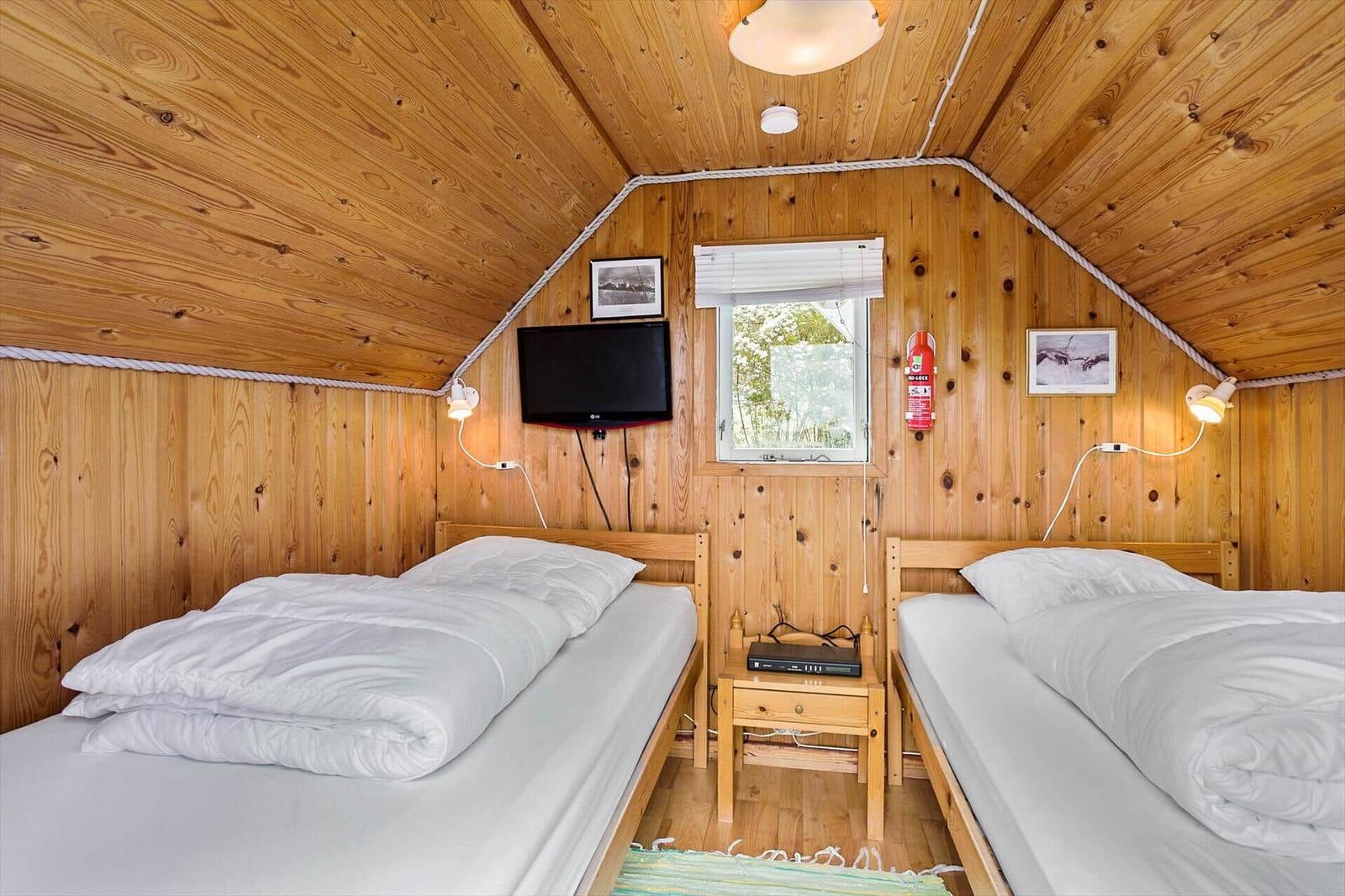 Two beds with white bedding, wooden walls, and a window.