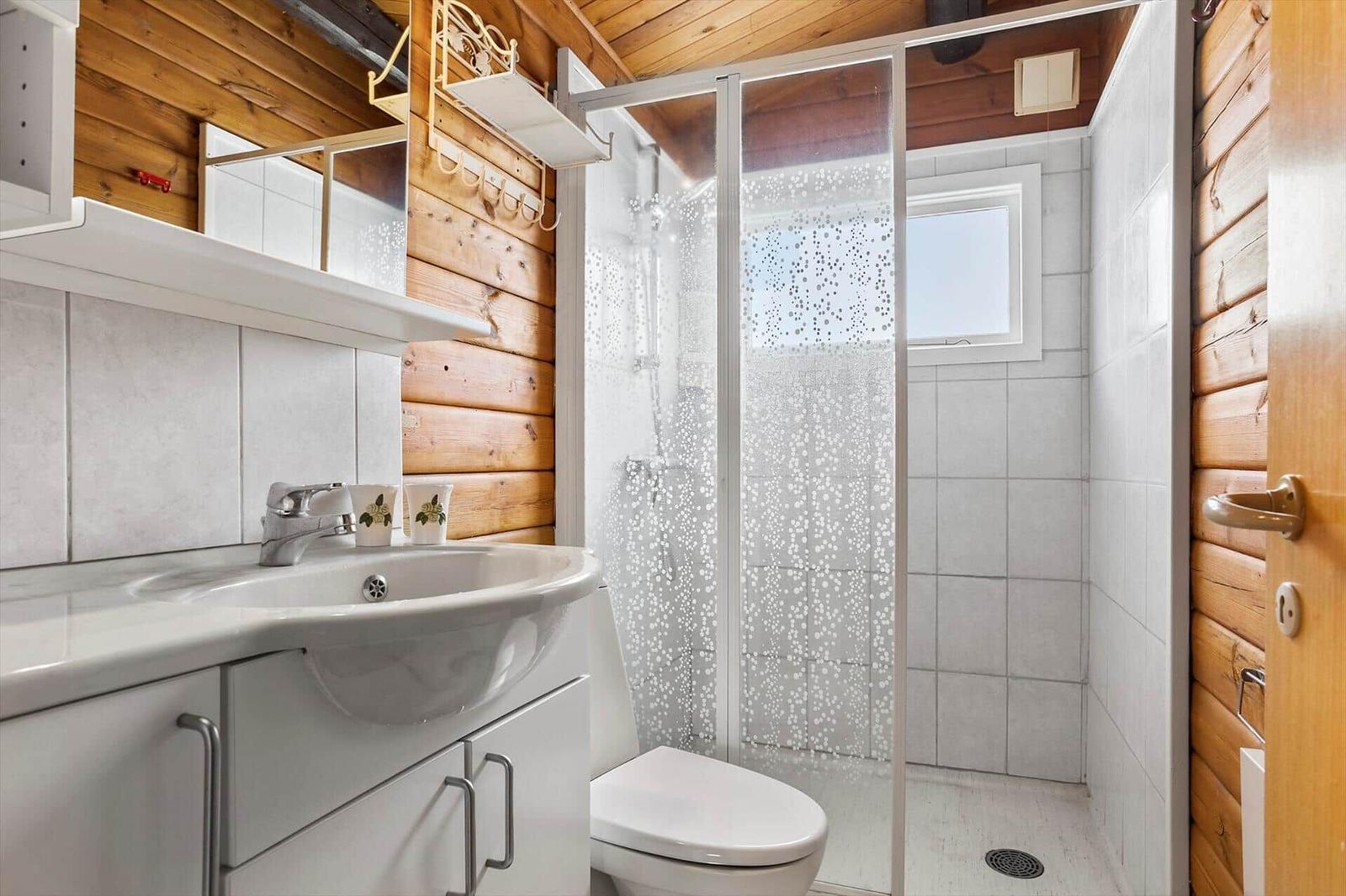 Bathroom with shower, sink and toilet. Wooden walls and tiles.