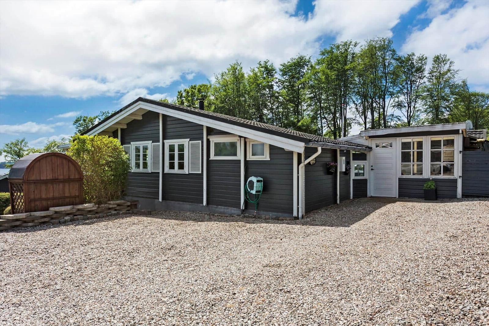 A dark gray house with white window frames and a garden door. A gravel area lies in front of the house.