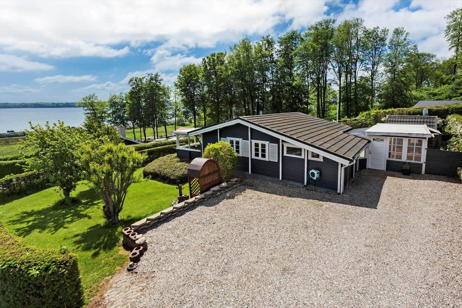 A house with a view of a lake, surrounded by lawns and trees.