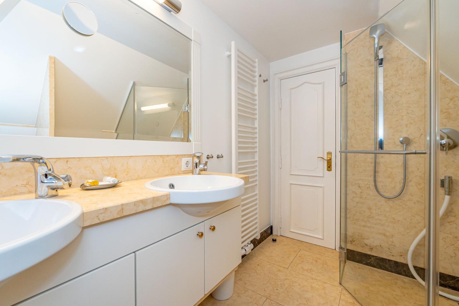 Badezimmer mit Dusche, Waschbecken und Spiegel.