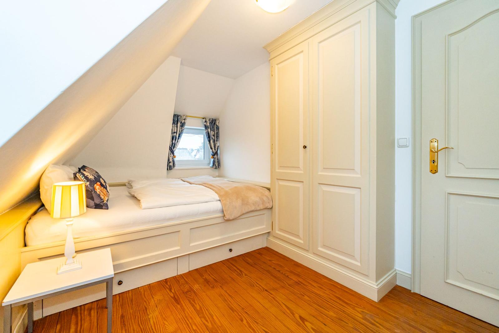 Dachgeschosszimmer mit Bett, Kleiderschrank und Holzboden
