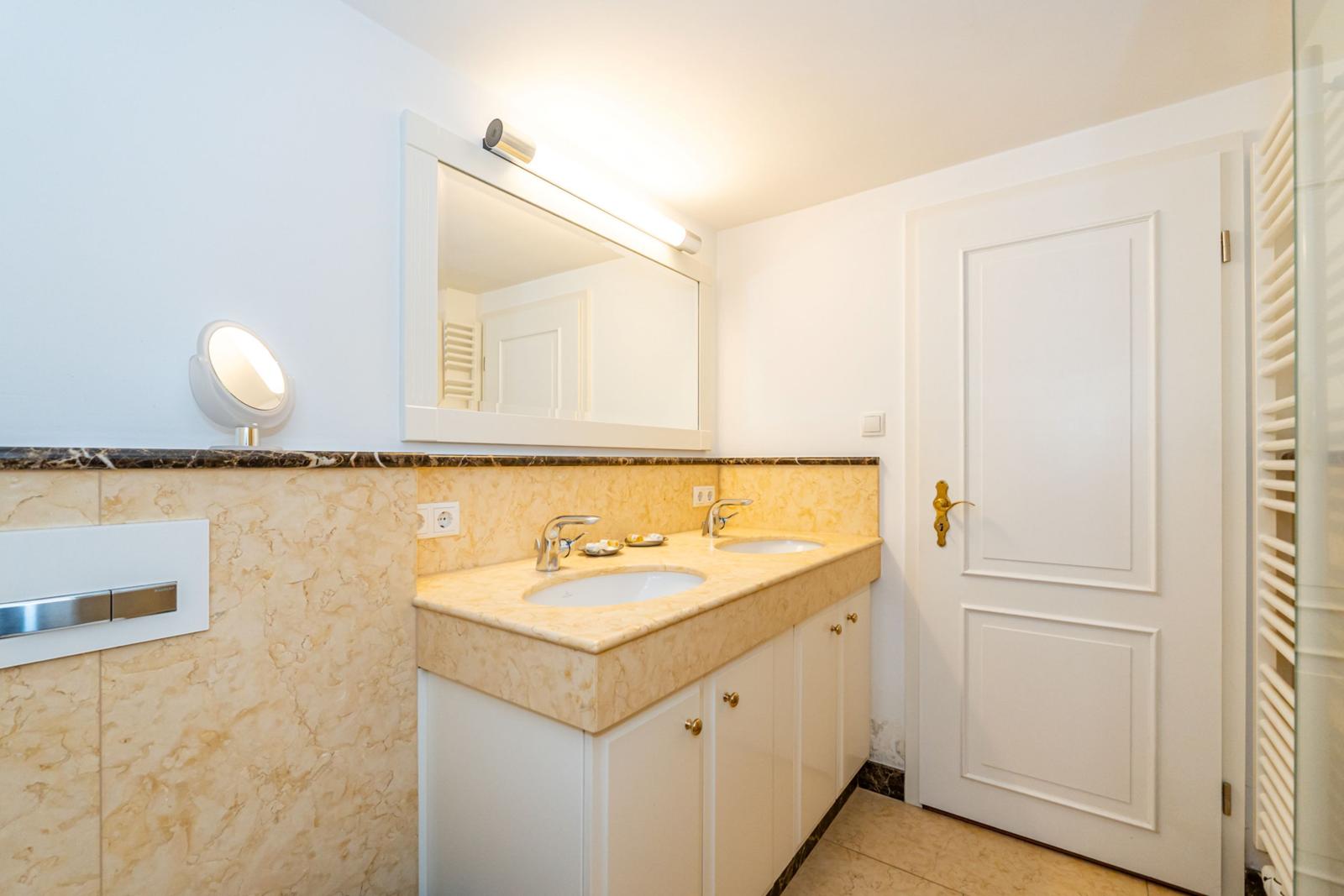 Bad mit Doppelwaschbecken, Spiegelschrank und Heizung.