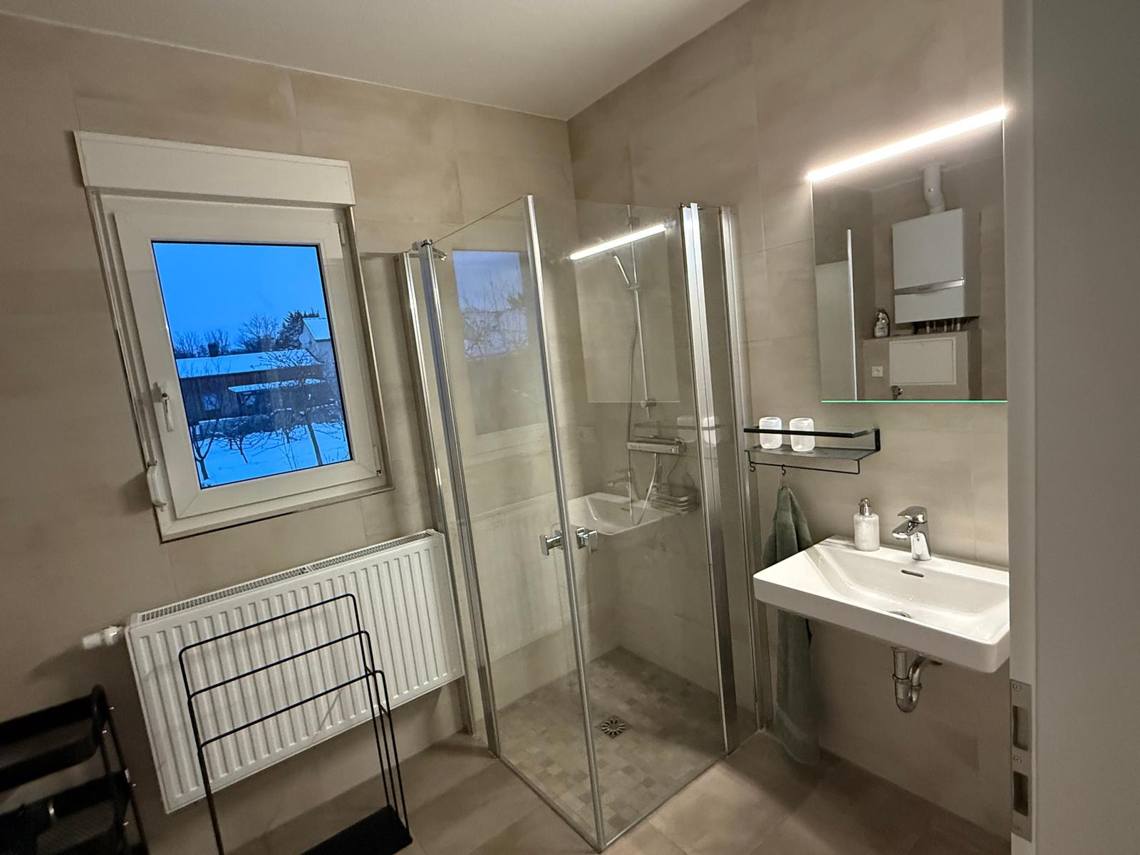 Badezimmer mit Dusche, Waschbecken und Fenster. Moderne Einrichtung.