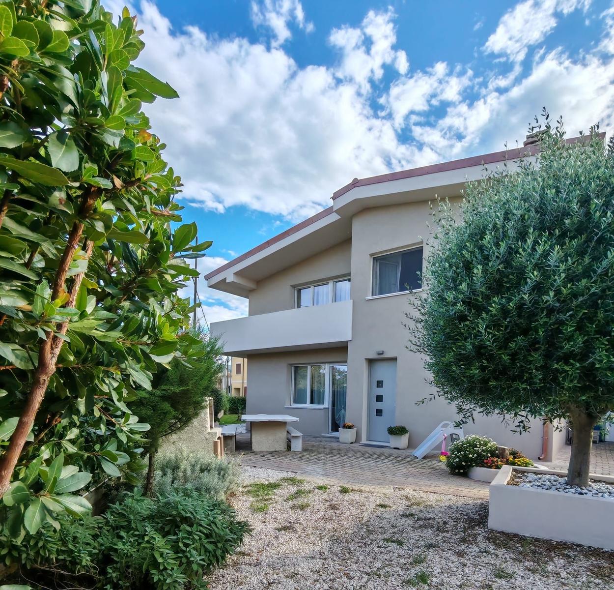 House with garden, terrace, and playground under blue sky.