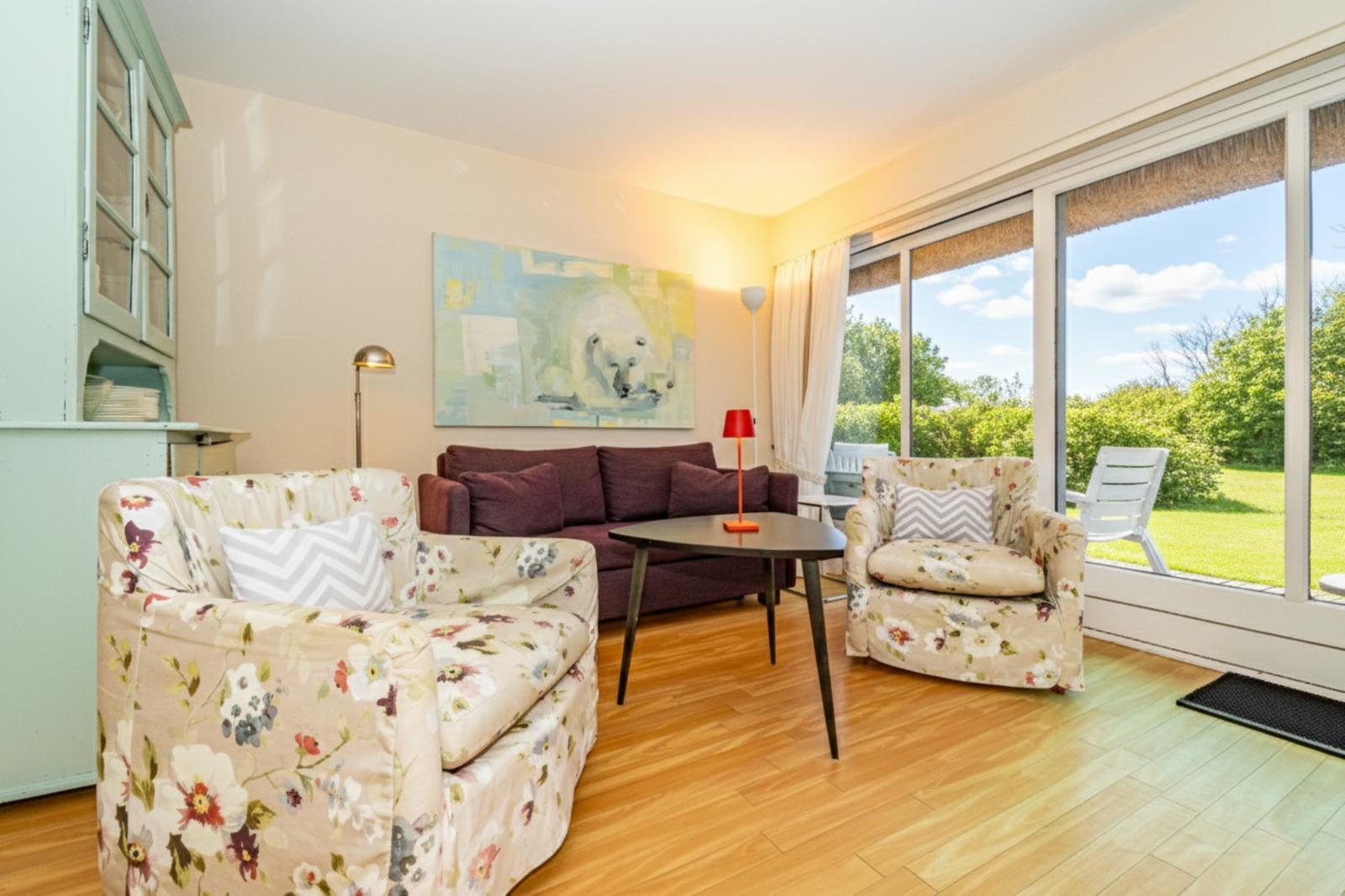 Wohnzimmer mit Sitzgelegenheiten und Blick auf den Garten.