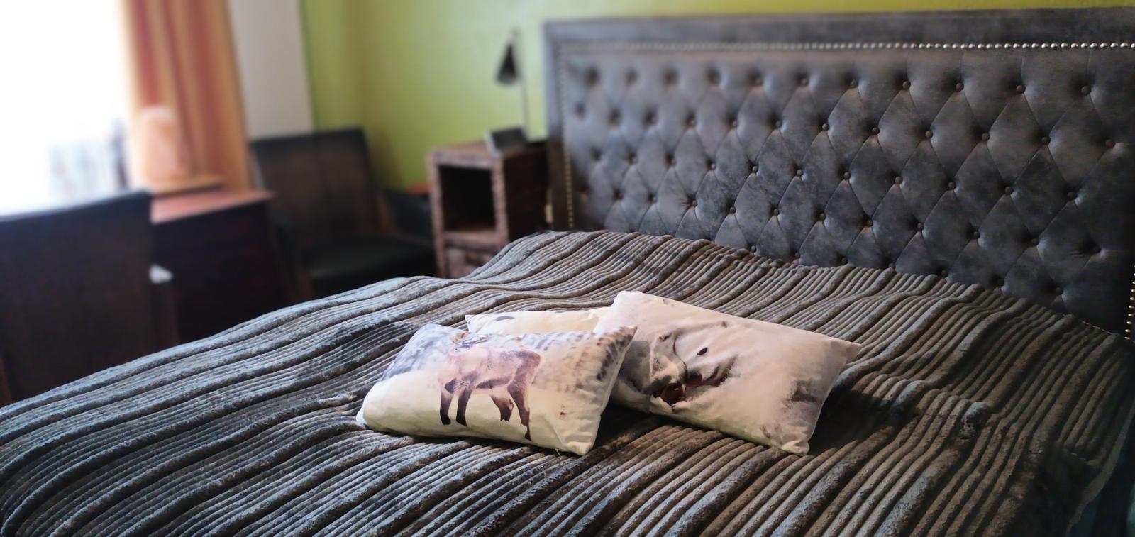 Ein Bett mit gesteppter Kopfseite und Kissen mit Tiermotiven.