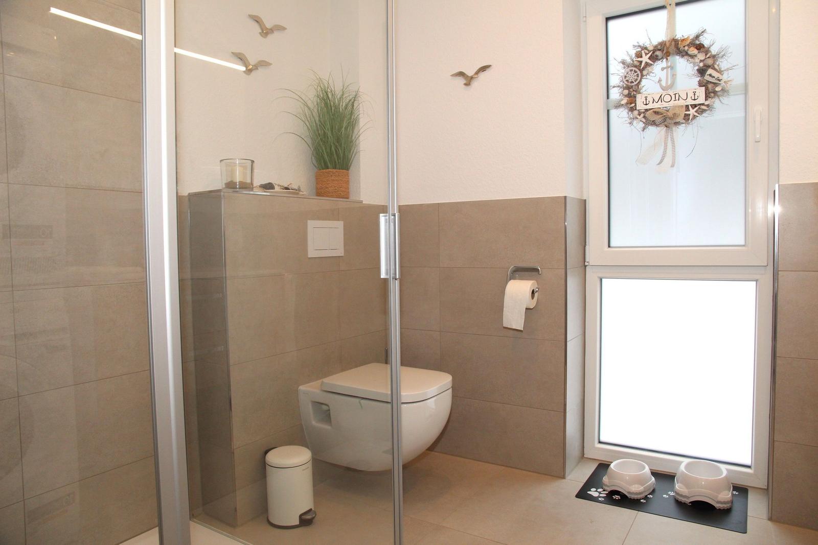 Bad mit Dusche, WC und Fenster mit Dekor.