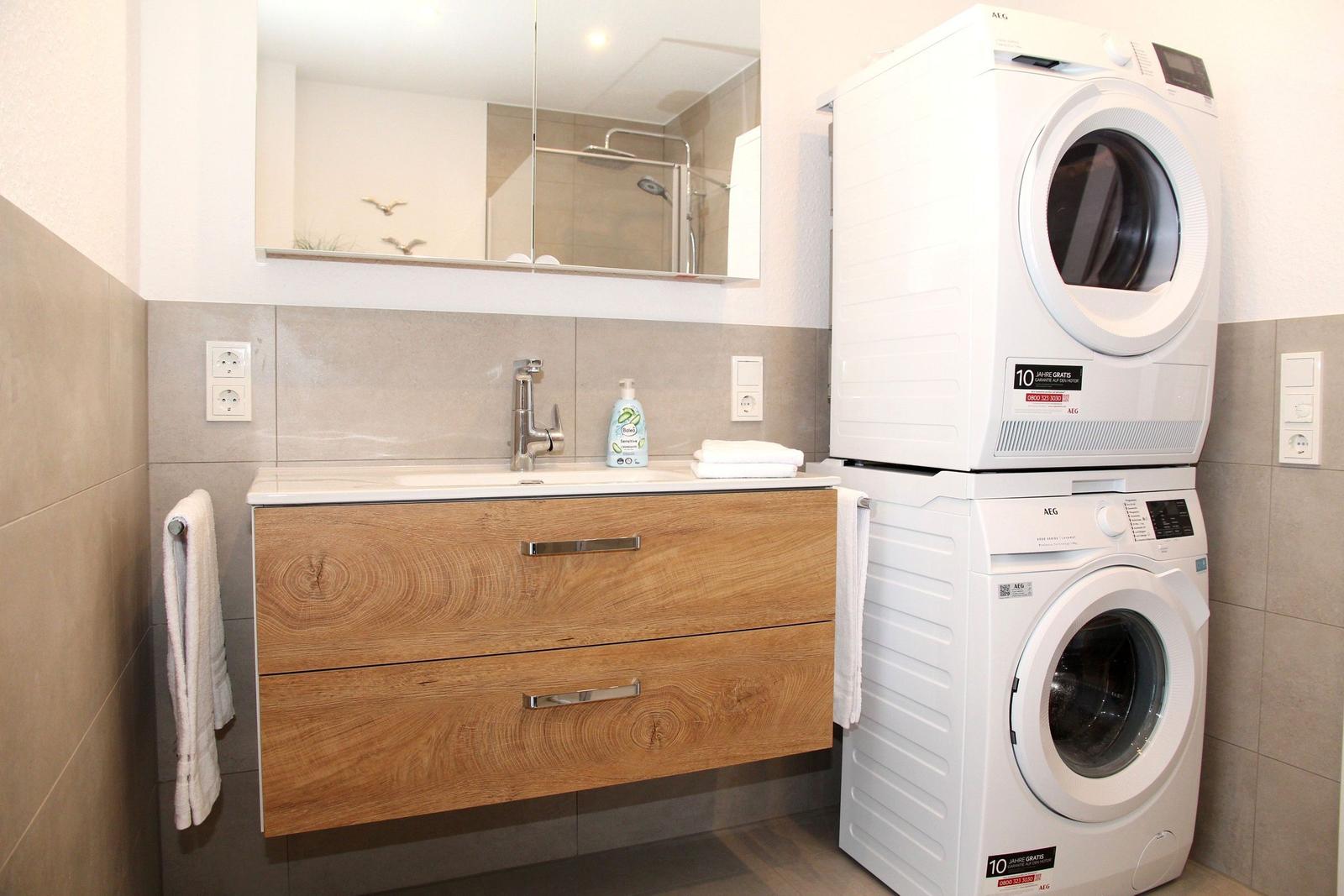 Badezimmer mit Waschmaschine und Trockner. Holzwaschtisch und Spiegel.