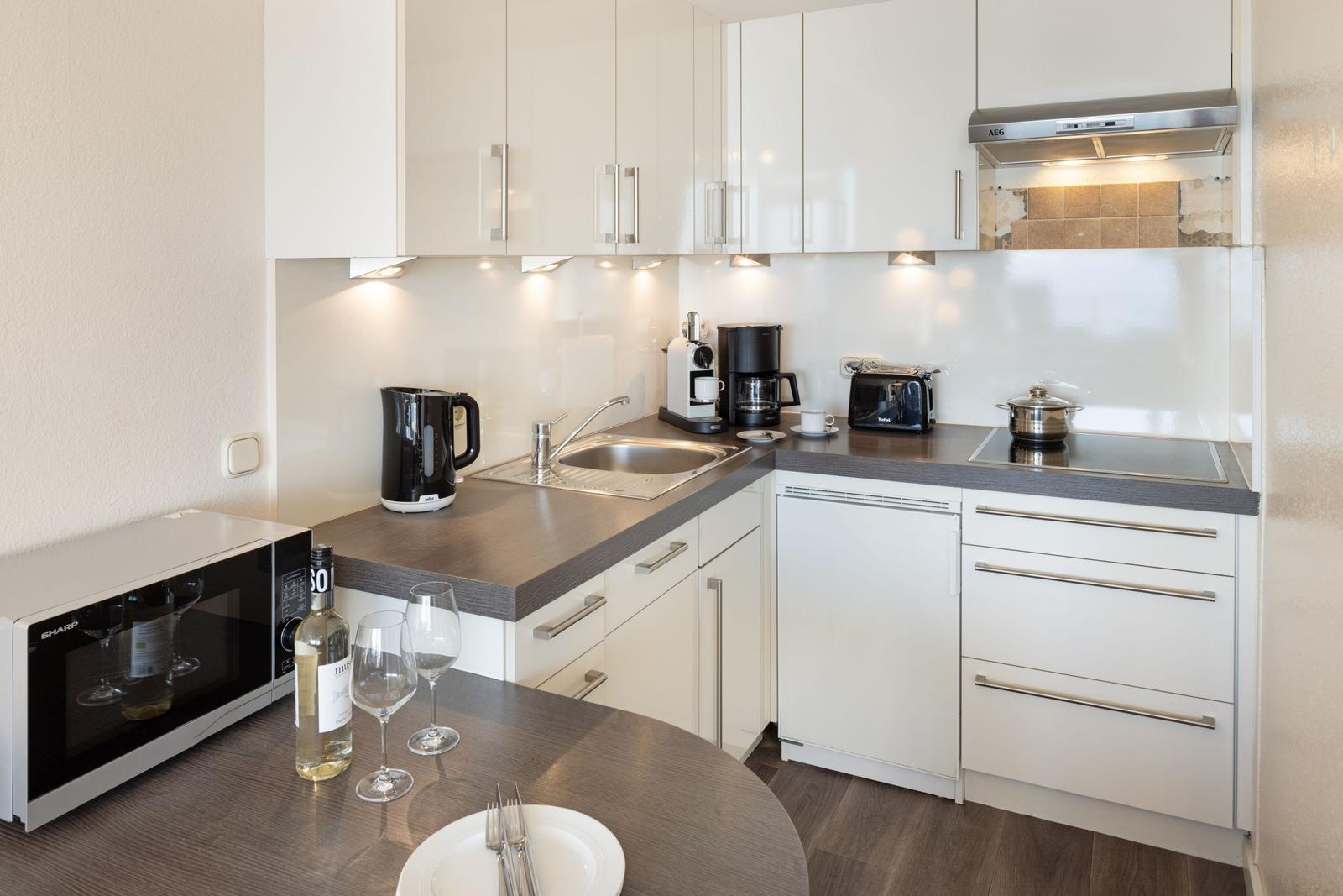 Küche mit Arbeitsplatte, Spüle, Kochfeld und Geräten.