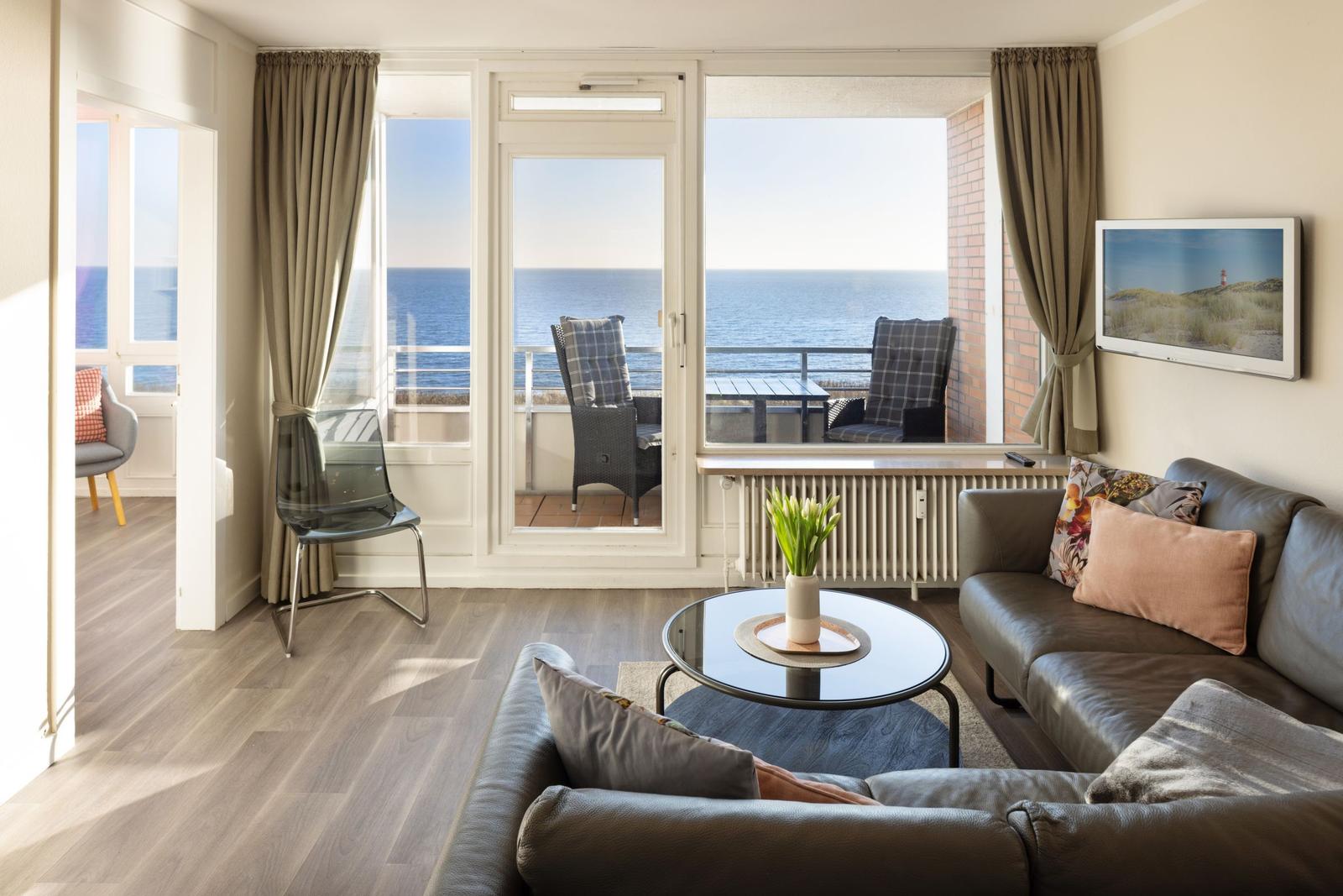 Wohnzimmer mit Blick aufs Meer und Balkon mit Sitzgelegenheiten.