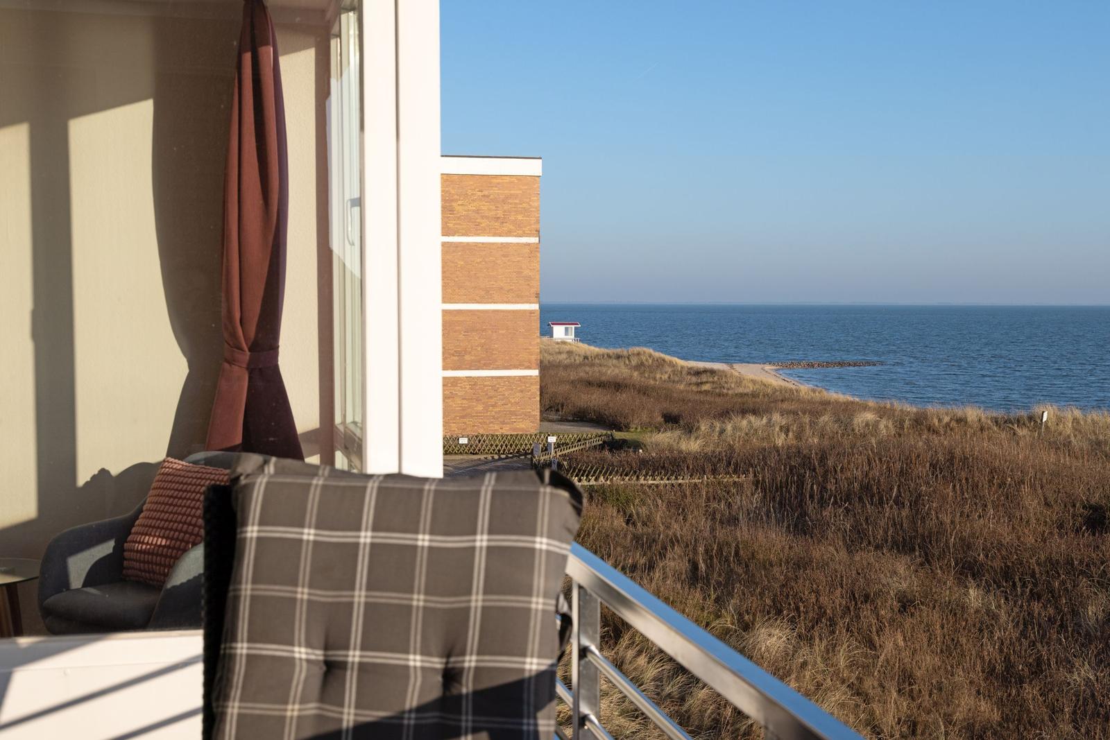 Balkon mit Sitzgelegenheiten und Blick auf das Meer und Dünen.