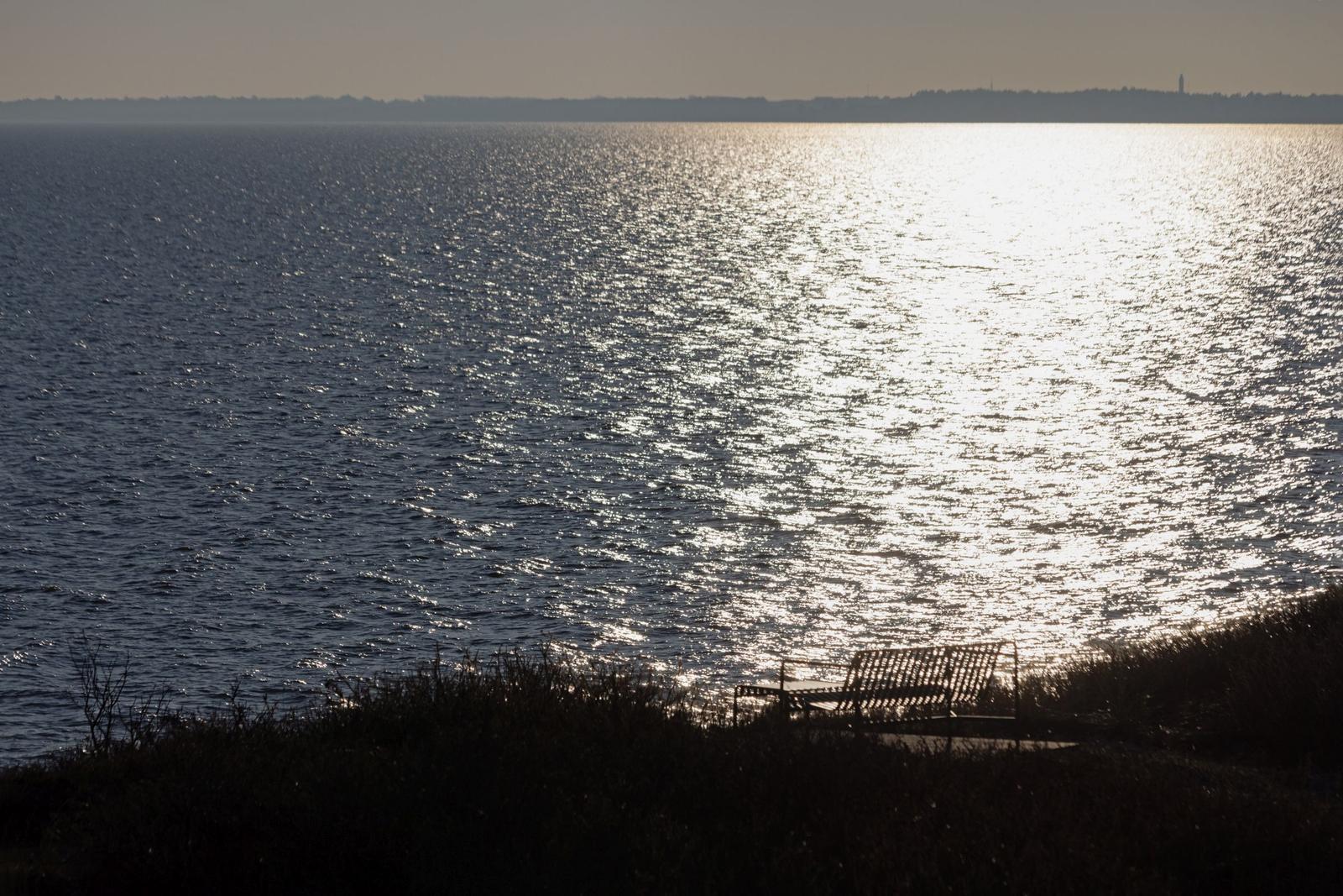 Ein Stuhl an einem Ufer mit Blick auf einen See bei Sonnenuntergang.