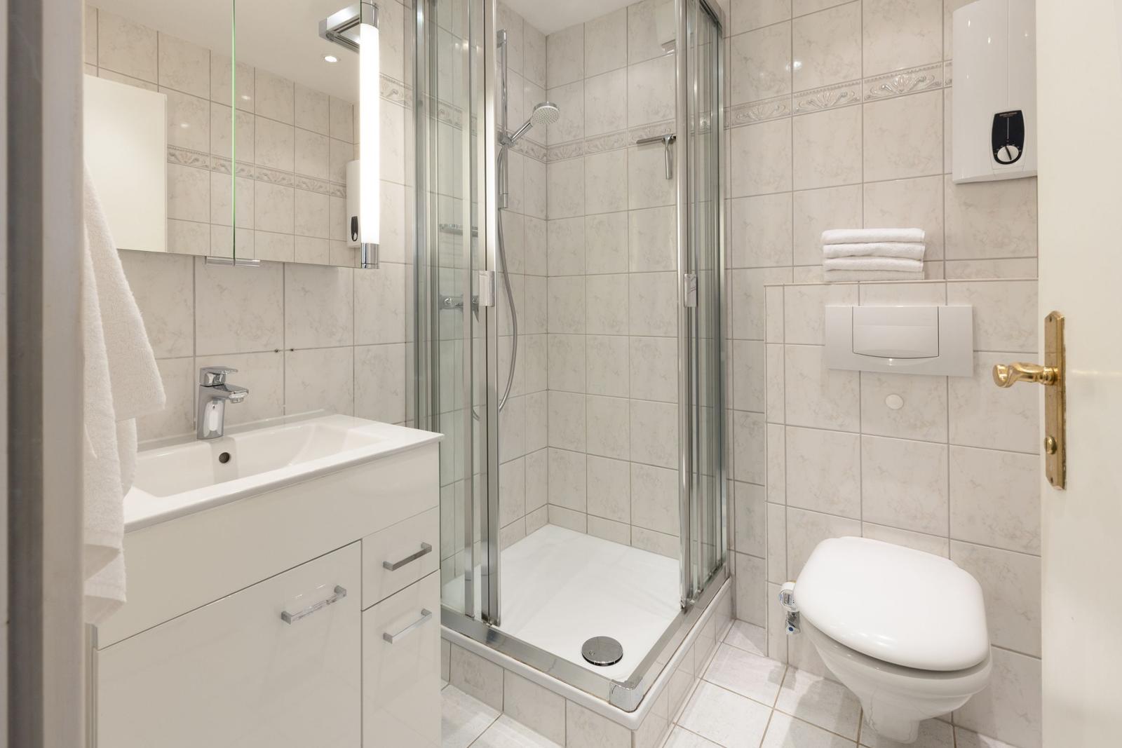 Badezimmer mit Dusche, Waschbecken und WC.