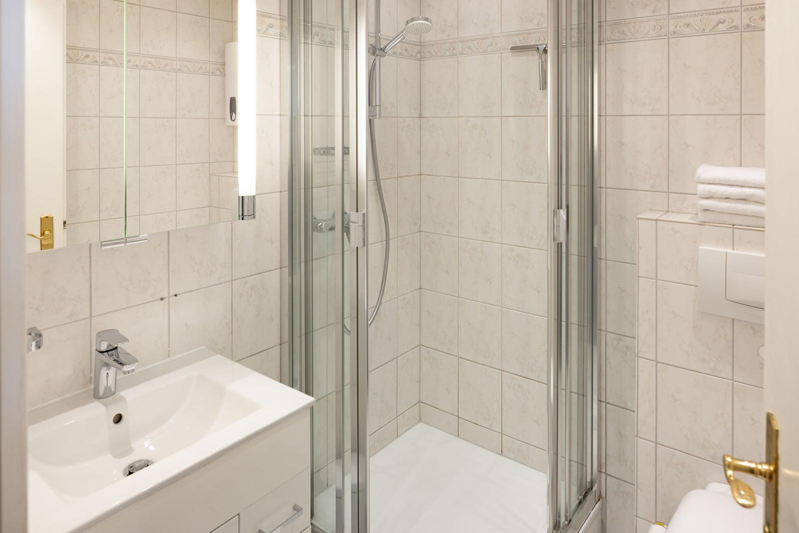 Badezimmer mit Dusche, Waschbecken und Toilette.