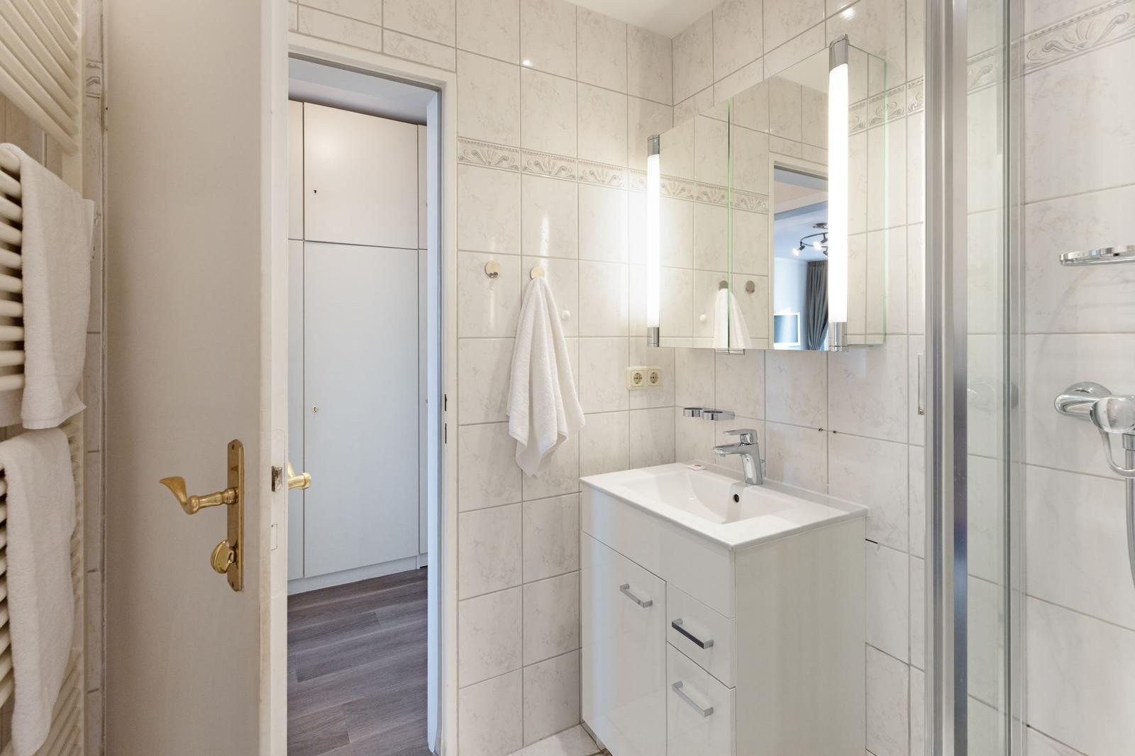 Badezimmer mit Dusche, Waschbecken und Spiegel