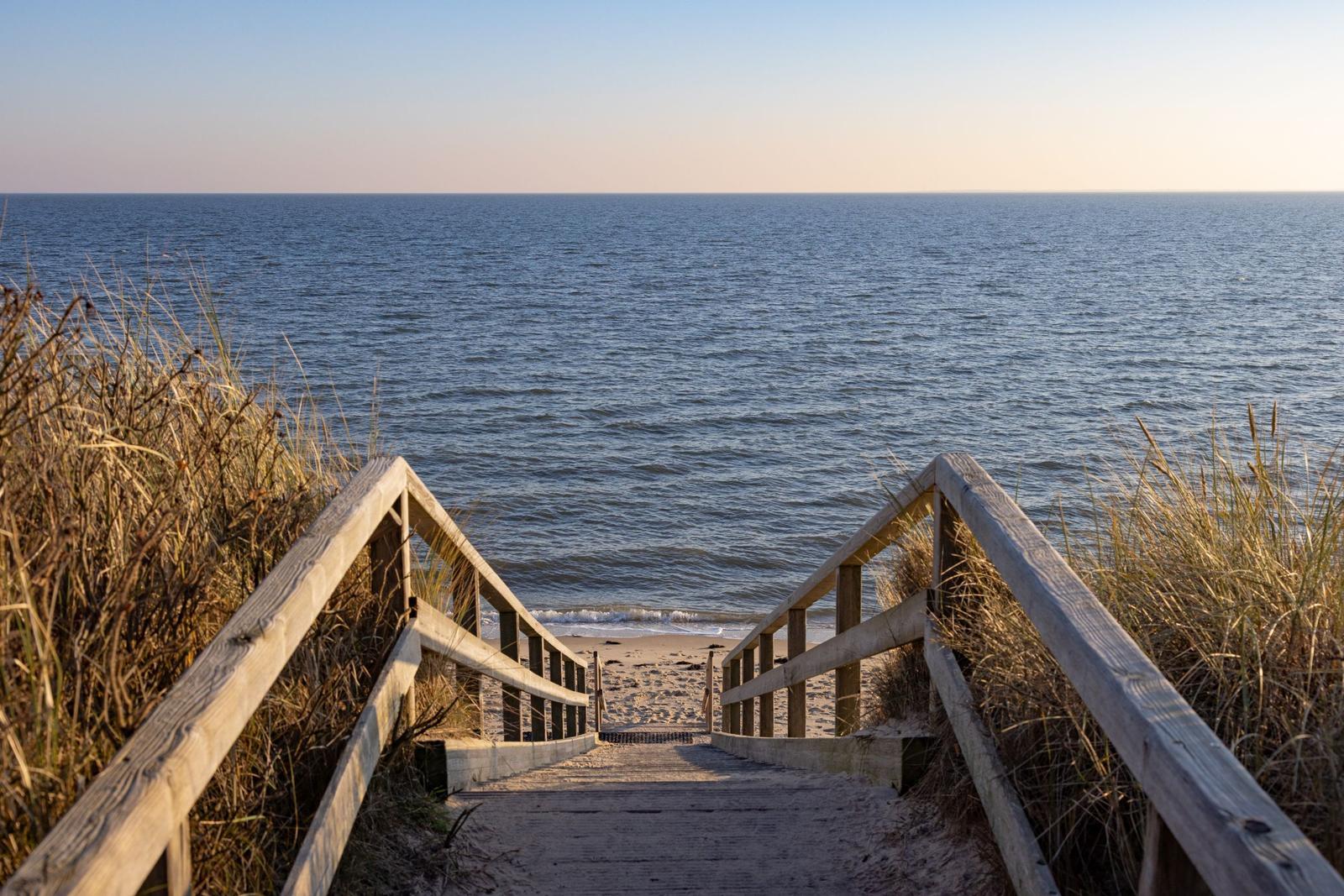 Holzsteg führt vom Strandhang zum Meer.