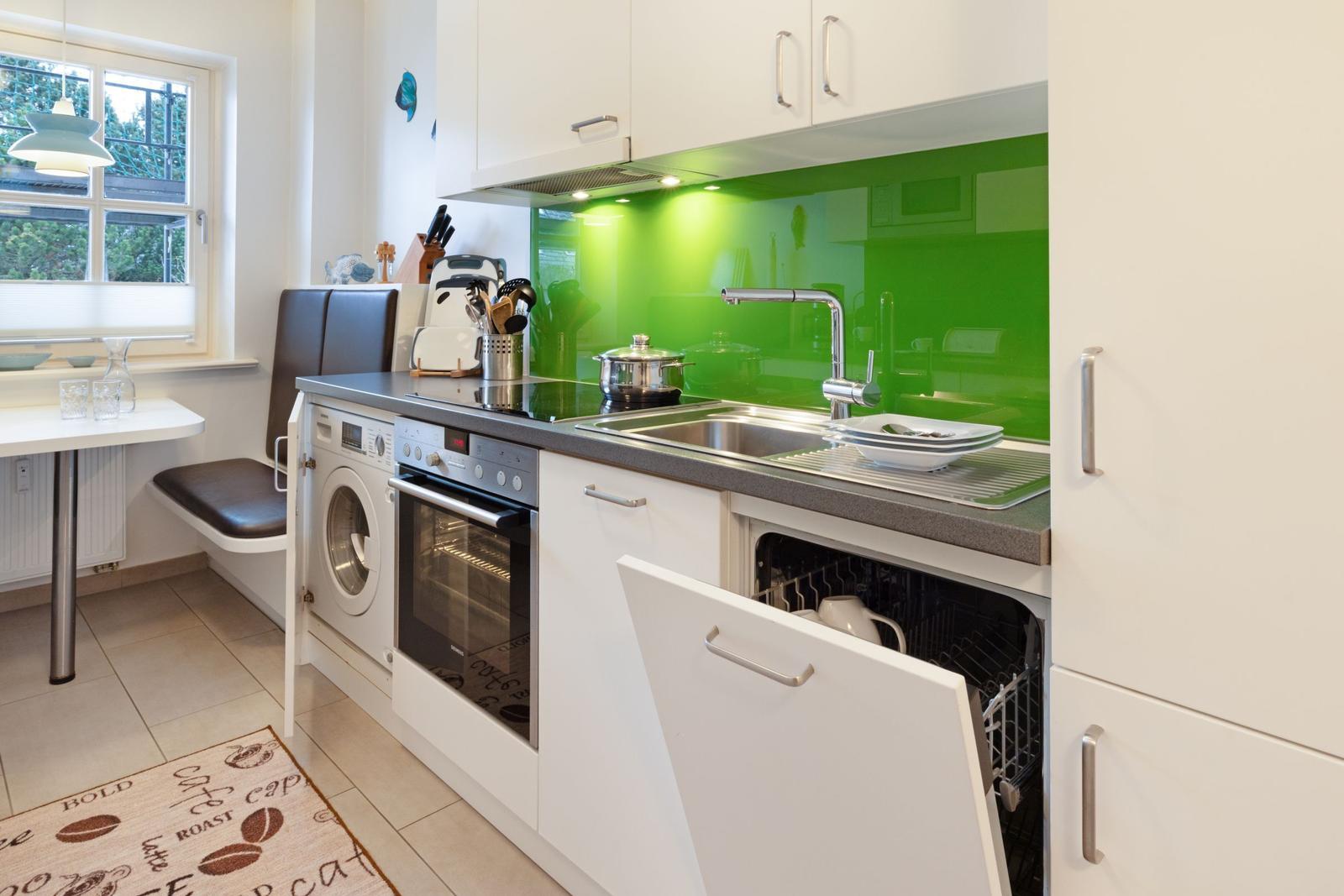 Küche mit grünem Hintergrund, Spüle, Herd und integriertem Geschirrspüler.