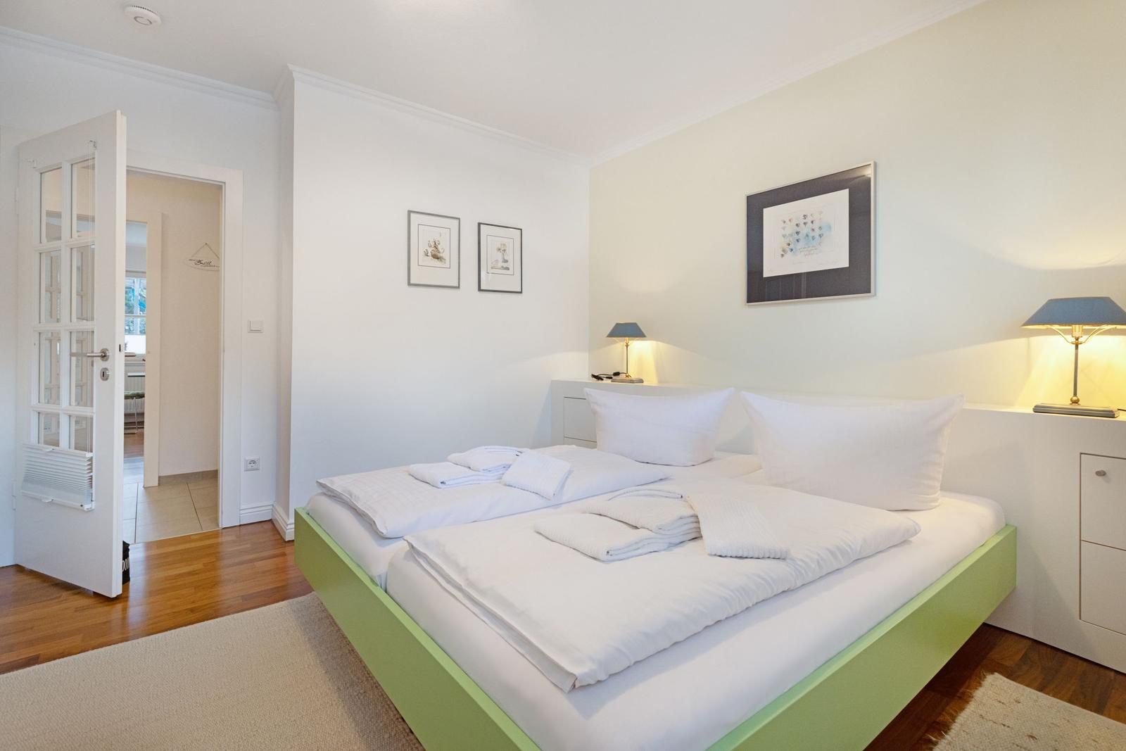 Schlafzimmer mit Bett, Nachttischen und Bildern an der Wand.