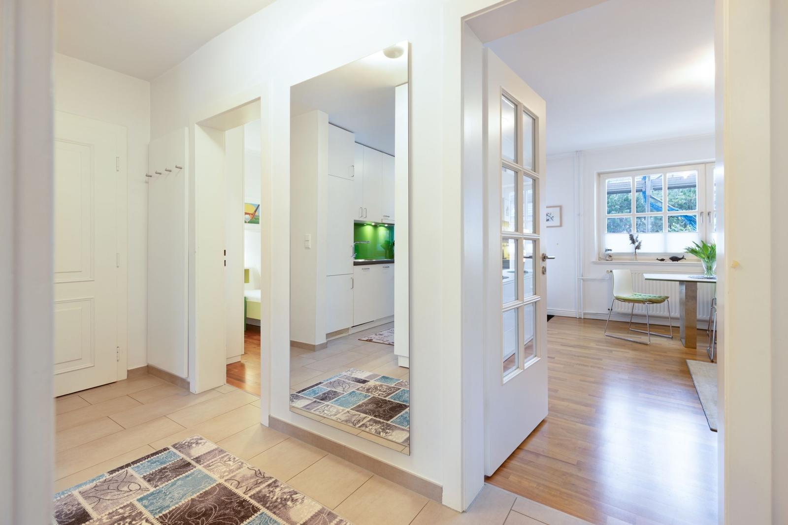 Eingangsbereich mit Blick in Küche und Esszimmer. Holzboden und weiße Wände.