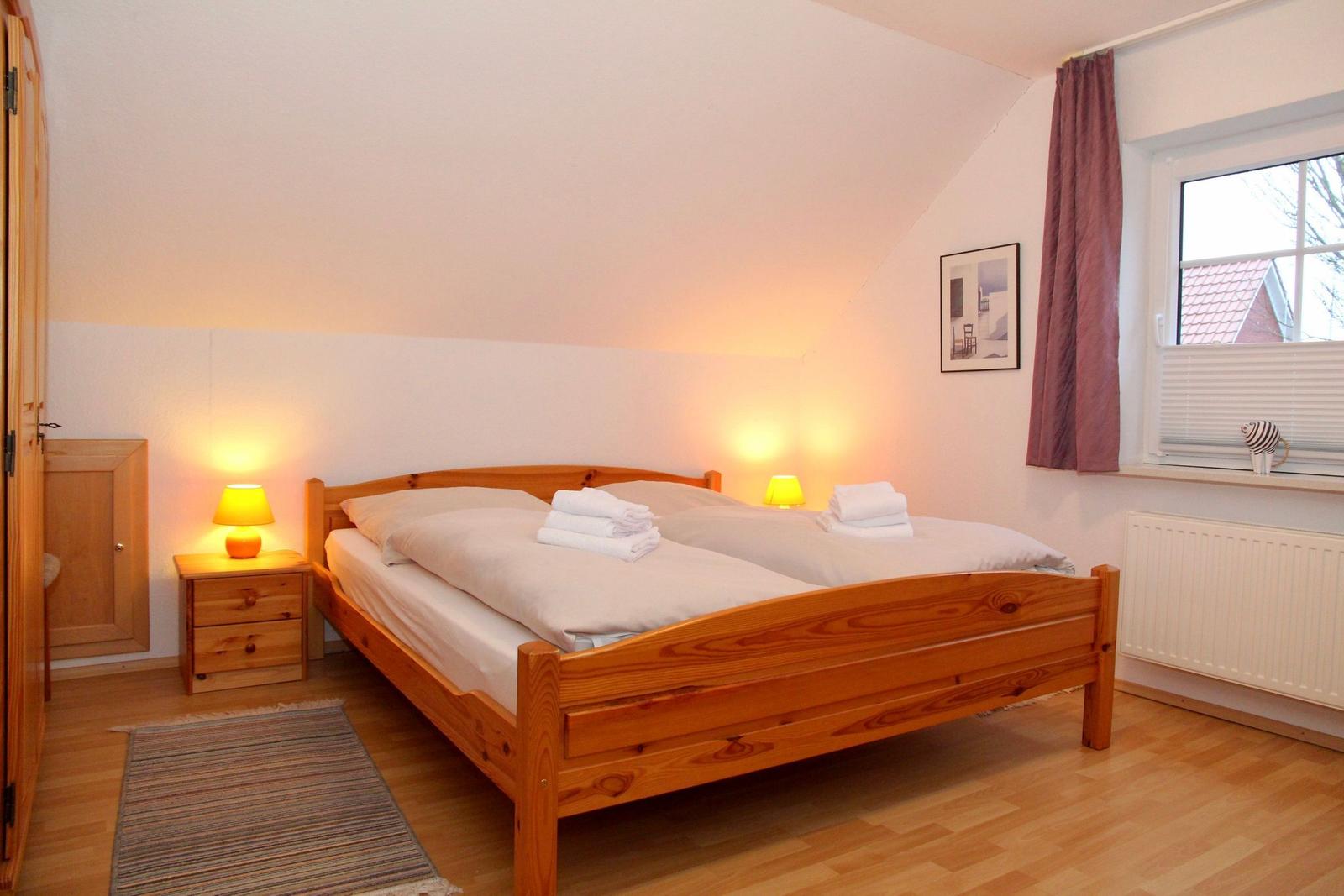 Ein Schlafzimmer mit Holzbett, Nachttischen und Fenster.