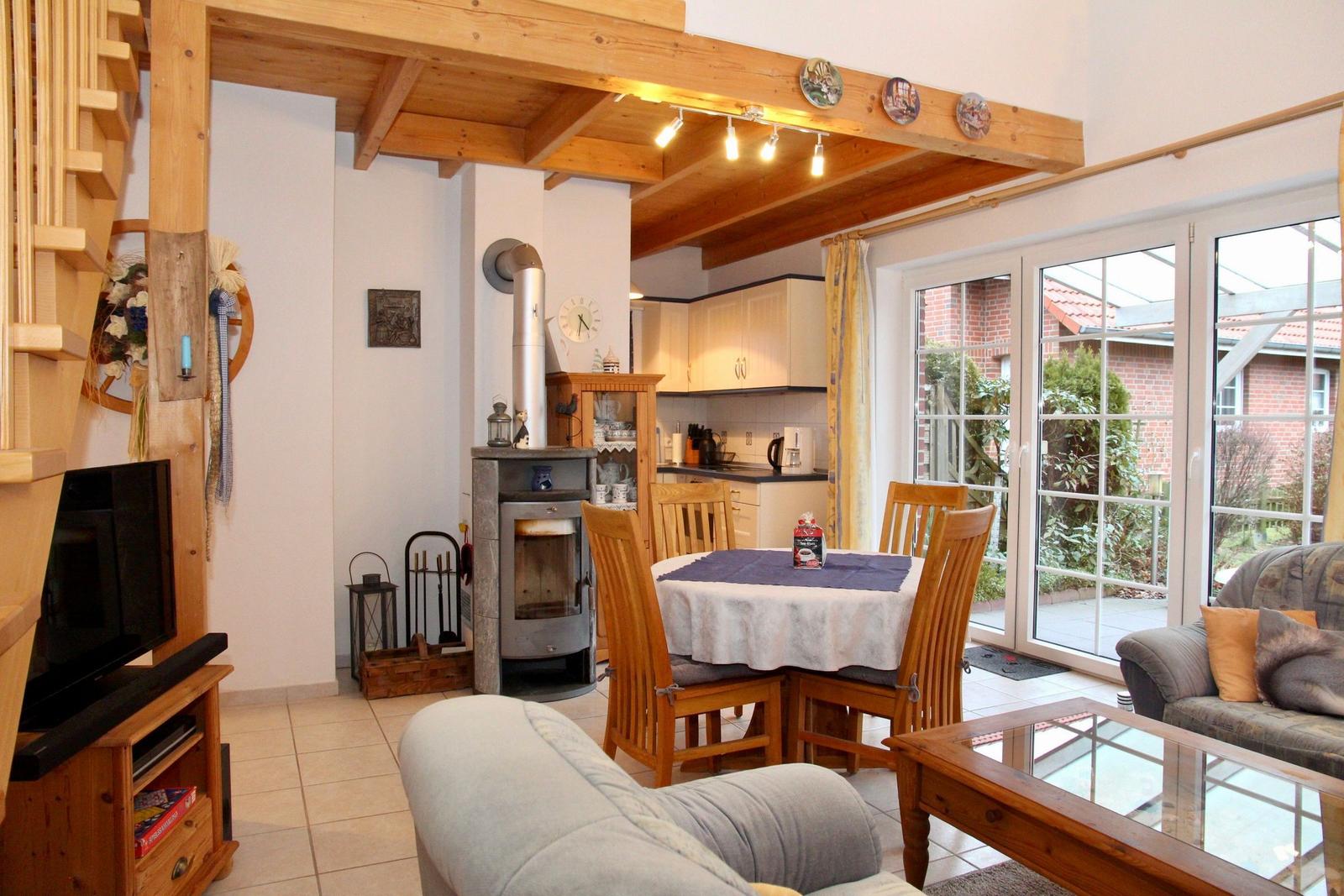 Wohn- und Essbereich mit Holzrahmen, Kamin und Glastüren zum Garten.