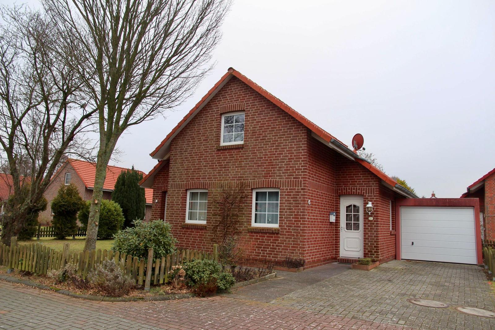 Rotes Backsteingebäude mit weißen Fenstern und Garagenbereich.