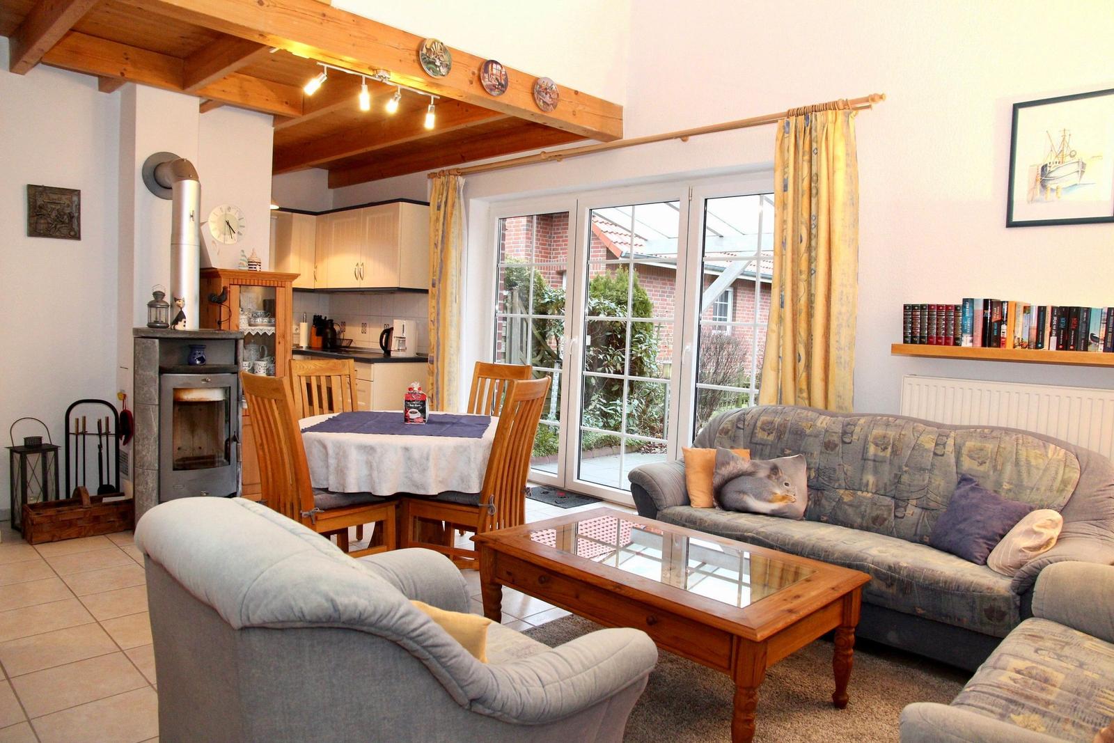 Wohn- und Essbereich mit Sofa, Couchtisch und Holzdecke. Durchgang zur Küche und Terrasse.