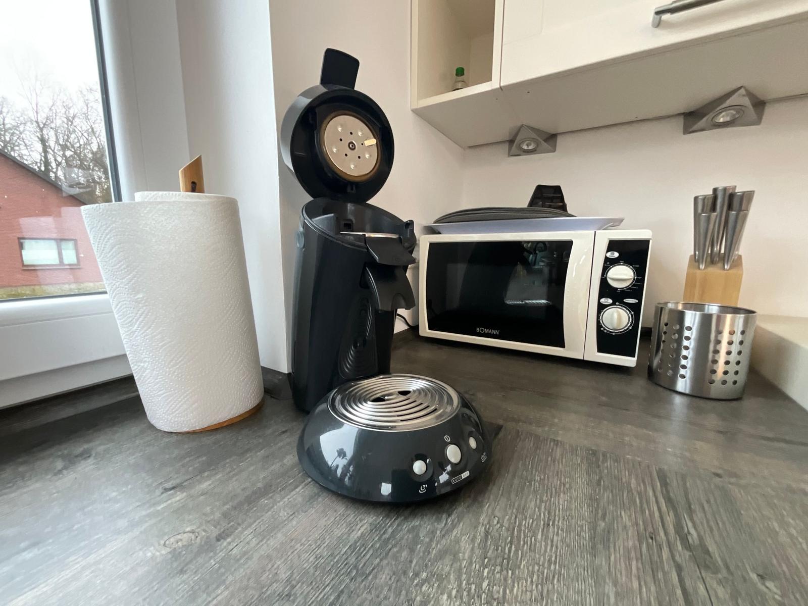 Küchenzeile mit Kaffeemaschine, Mikrowelle und Küchenutensilien.