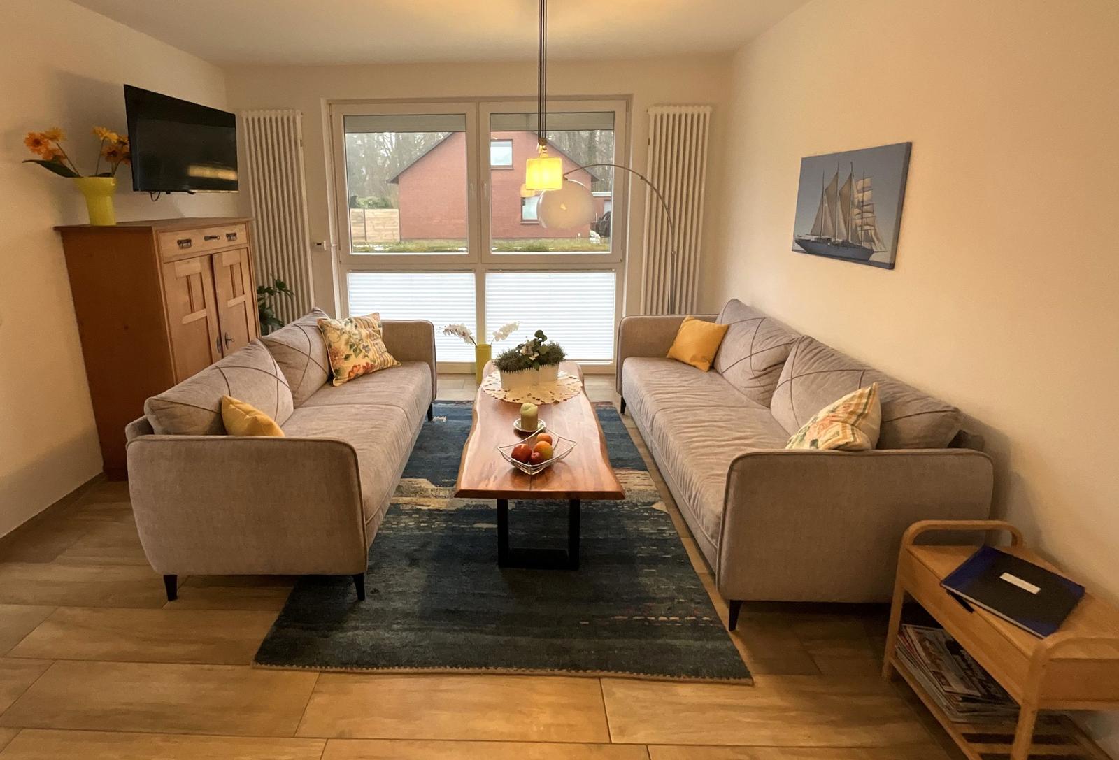 Wohnzimmer mit zwei Sofas, Holztisch und Fernseher an der Wand.