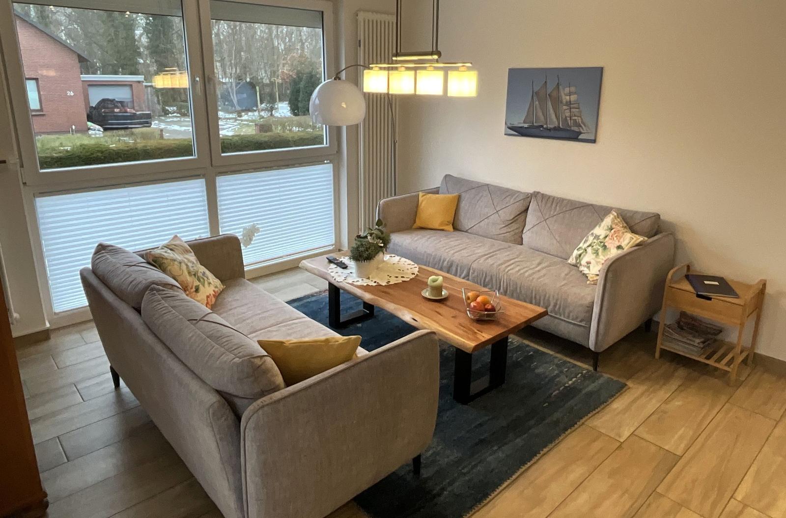 Wohnzimmer mit zwei Sofas, Holztisch und großen Fenstern.