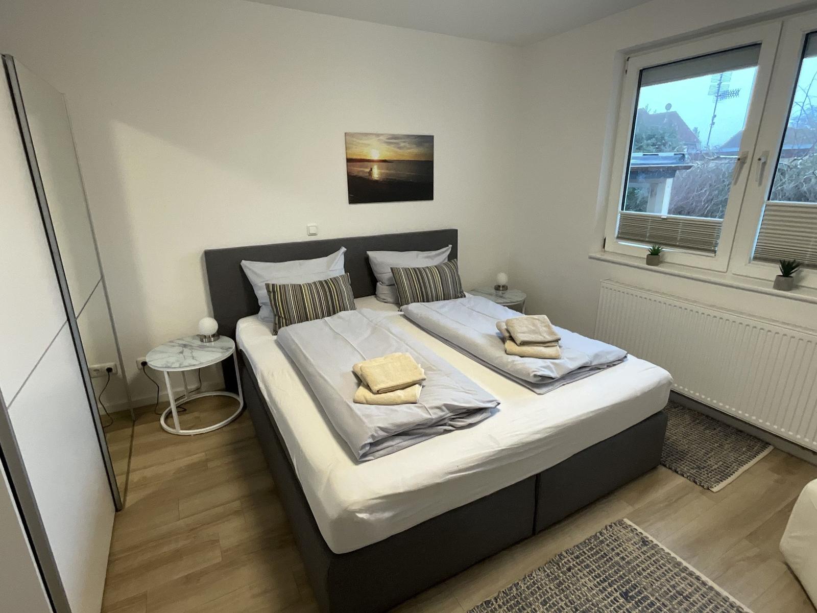 Schlafzimmer mit Doppelbett, Fenster und Kleiderschrank.