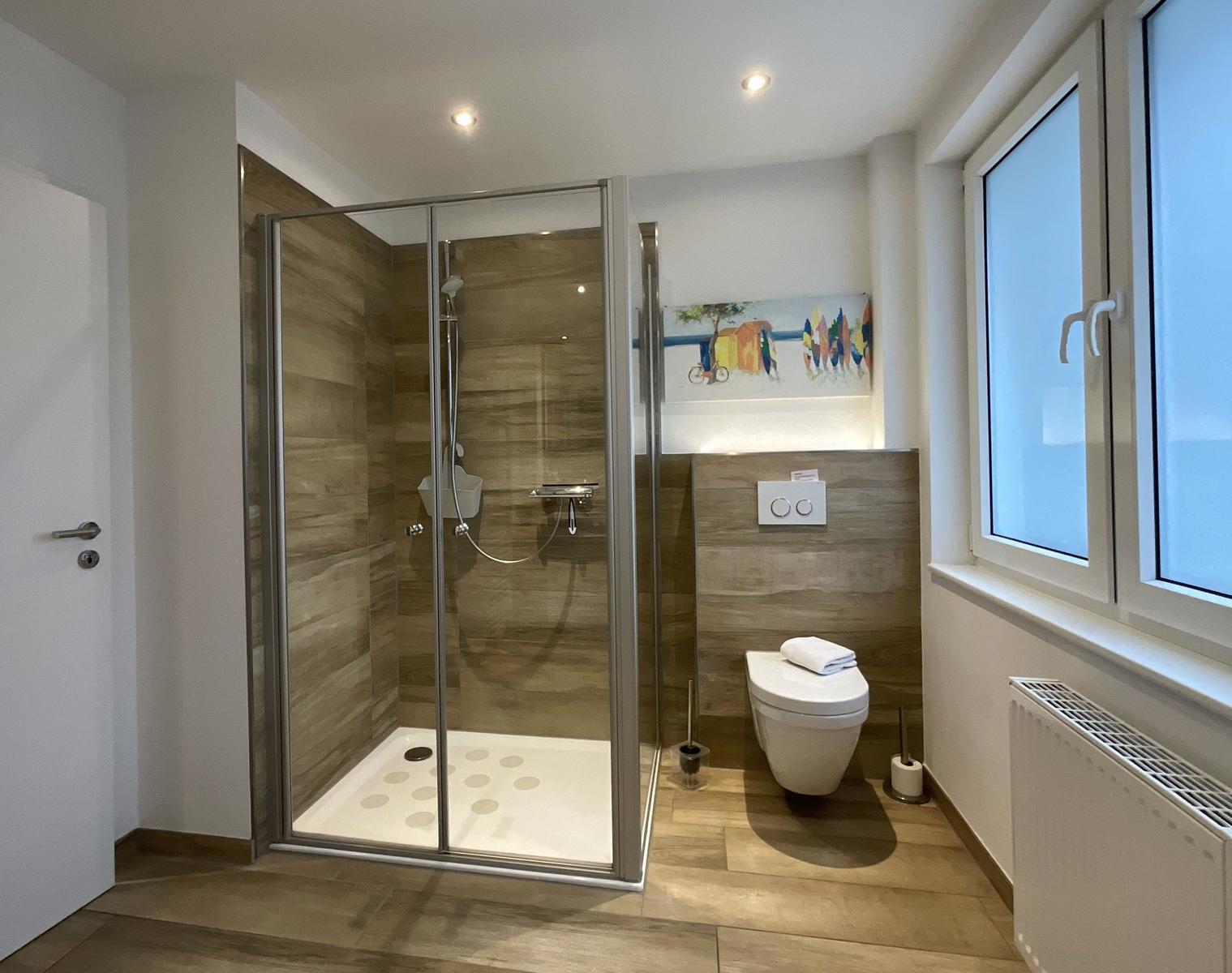 Badezimmer mit Dusche, Toilette und Fenster