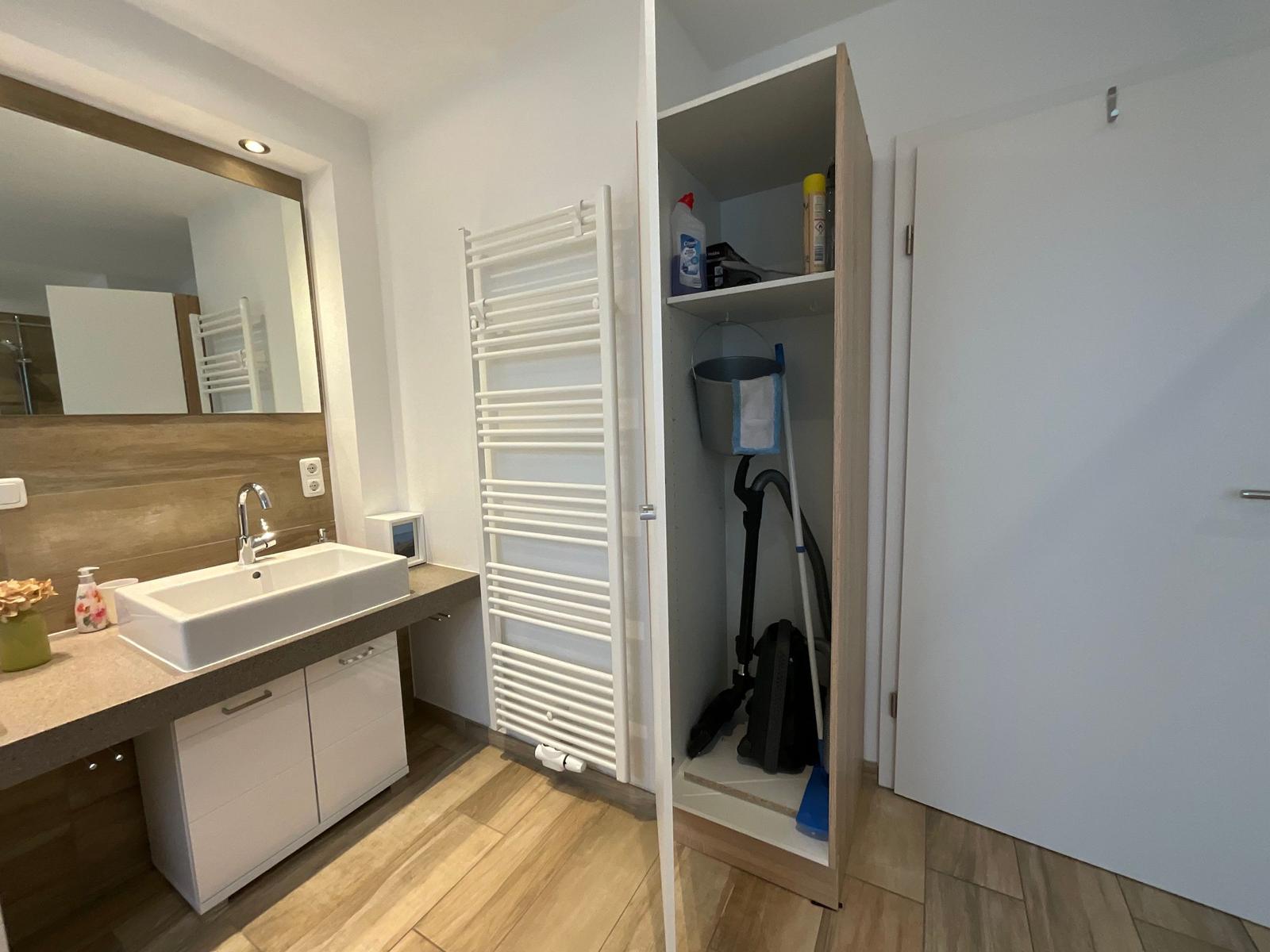 Badezimmer mit Waschbecken, Spiegel und Aufbewahrungsschrank.