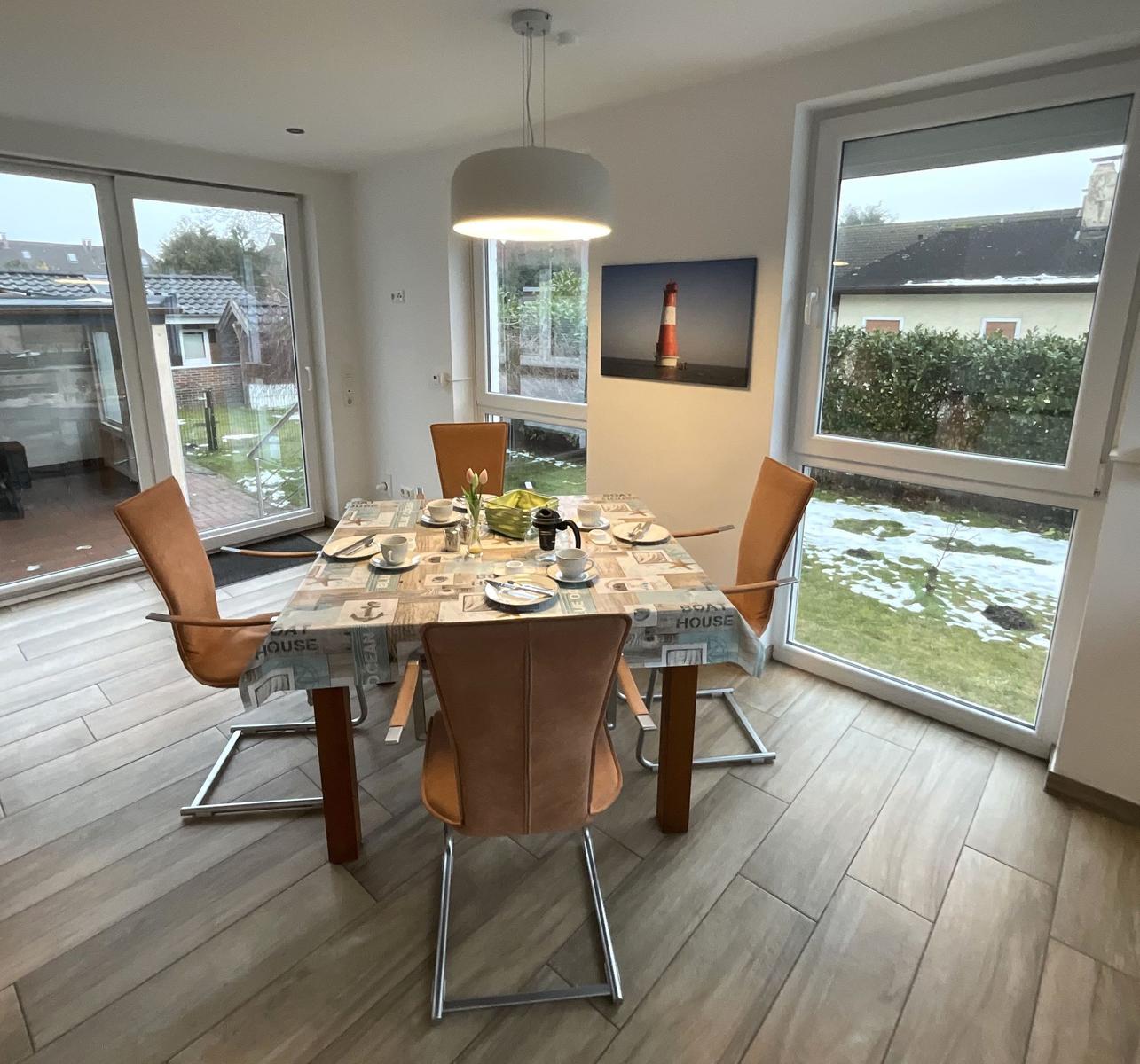 Esszimmer mit Tisch, Stühlen und großem Fensterblick auf Garten