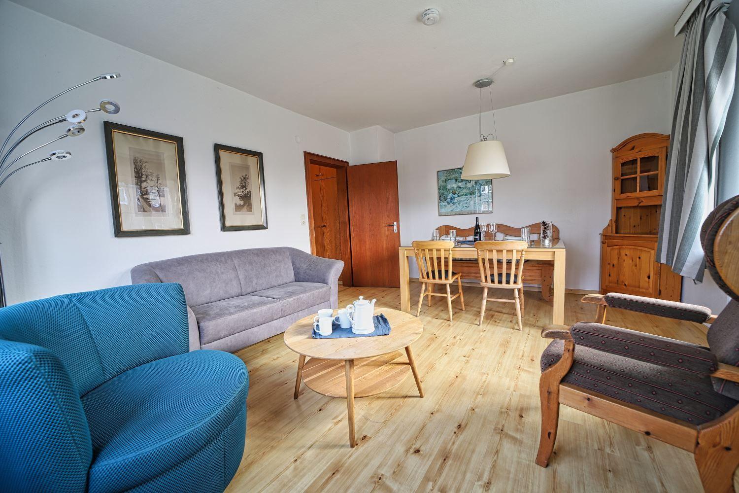 Wohn- und Essbereich mit Holzboden, Sofa, Stühlen und Tisch.