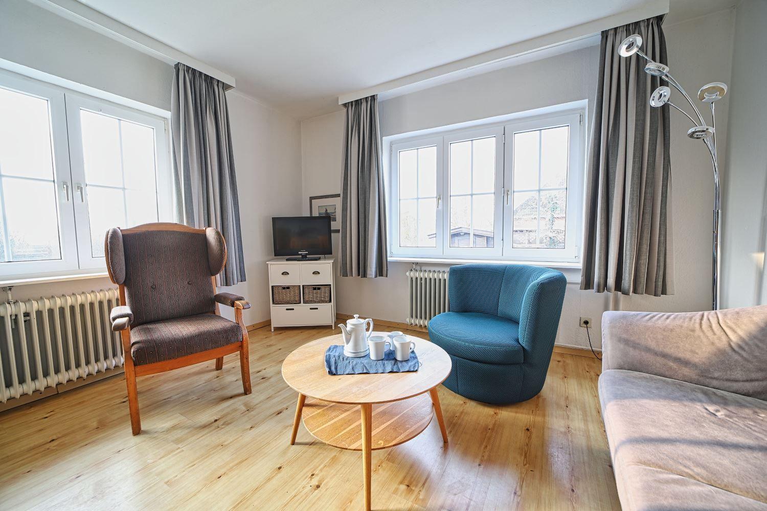 Wohnzimmer mit Sitzgelegenheiten, Tisch und Fenstern.