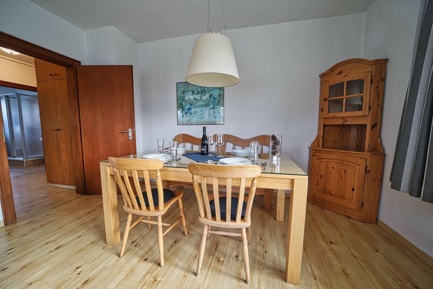 Esszimmer mit Holztisch, Stühlen und Sideboard. Hängelampe und Wandbild sichtbar.