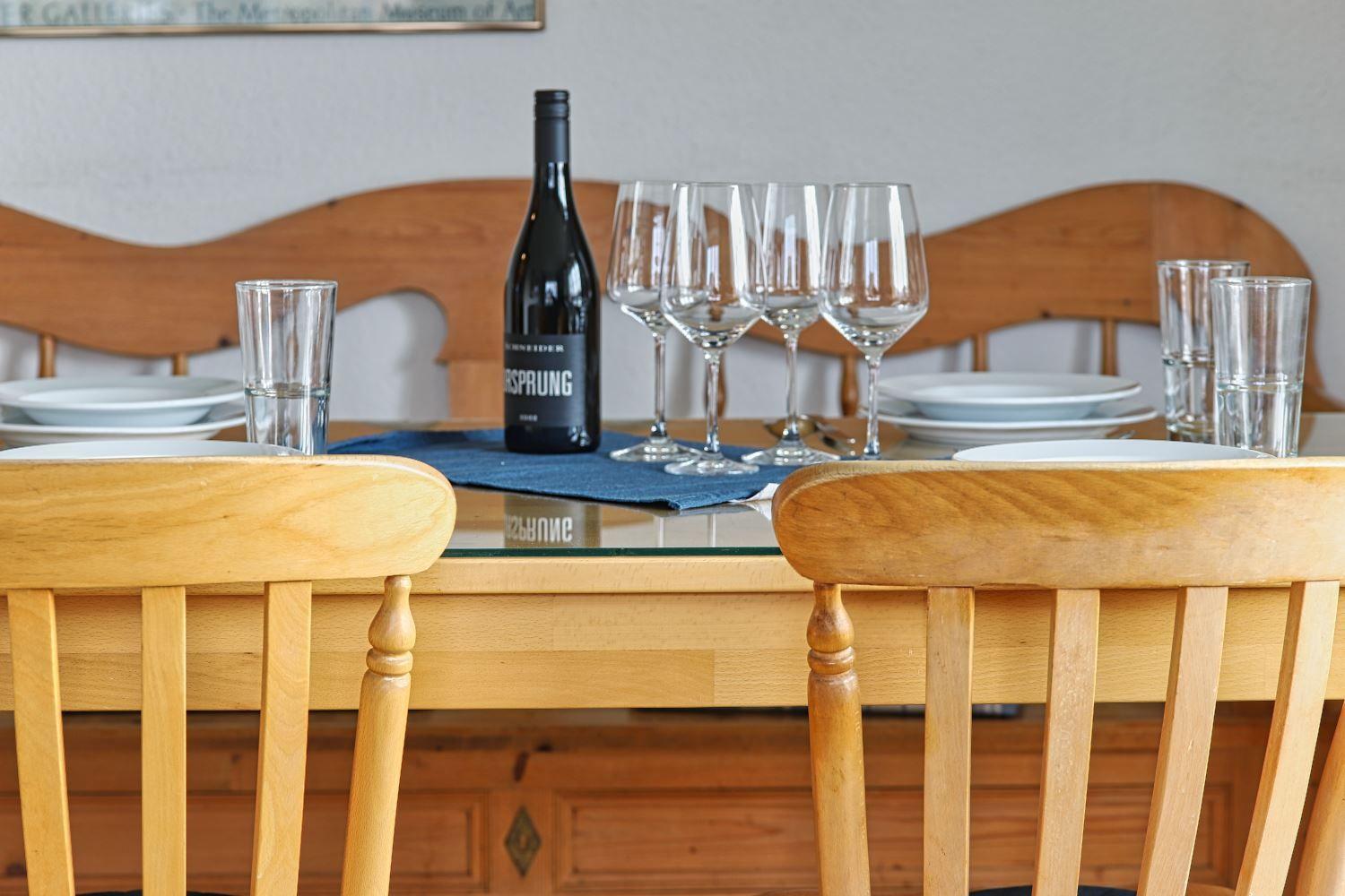 Esstisch mit Stühlen, Weinglas und Weinflasche