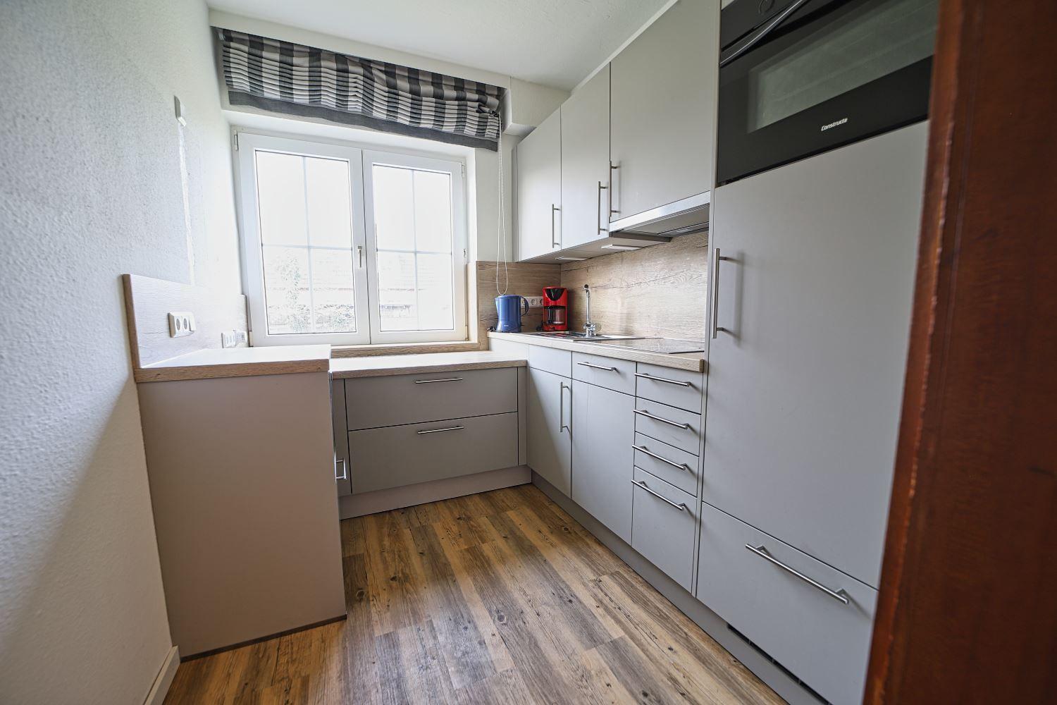 Küche mit Fenster, Schränken, Spüle und Kühlschrank.