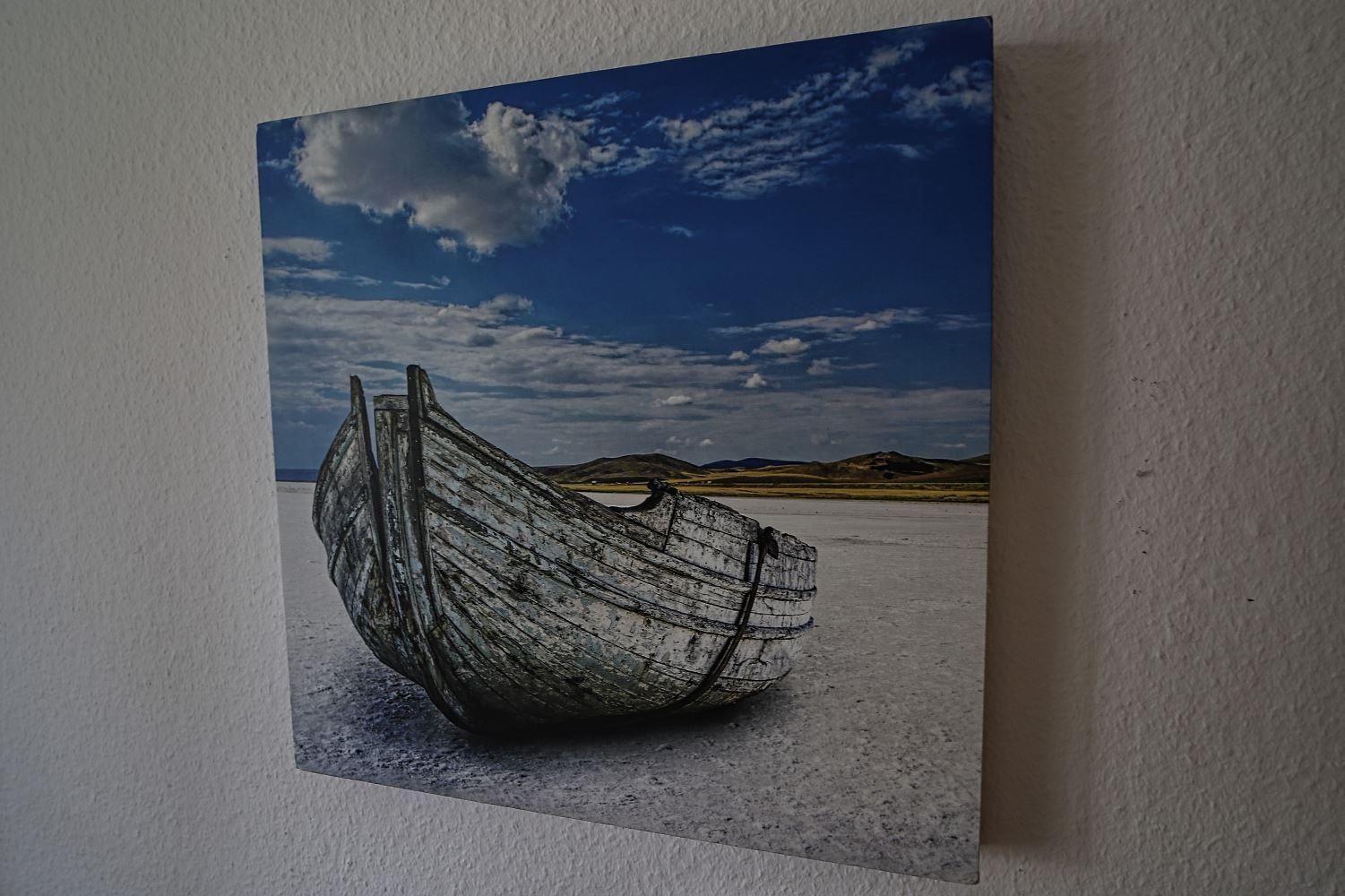 Ein altes Boot liegt auf einer salzhaltigen Fläche unter einem blauen Himmel mit Wolken.