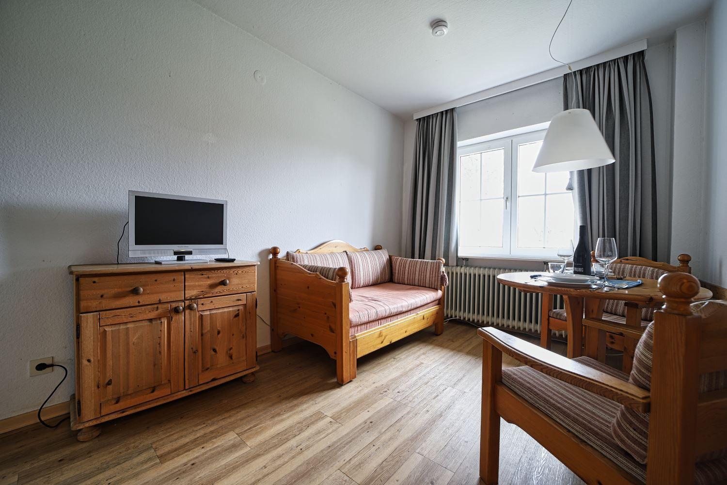 Ein Raum mit Holzmöbeln, Fernseher, Sofa und Tisch mit Stühlen.