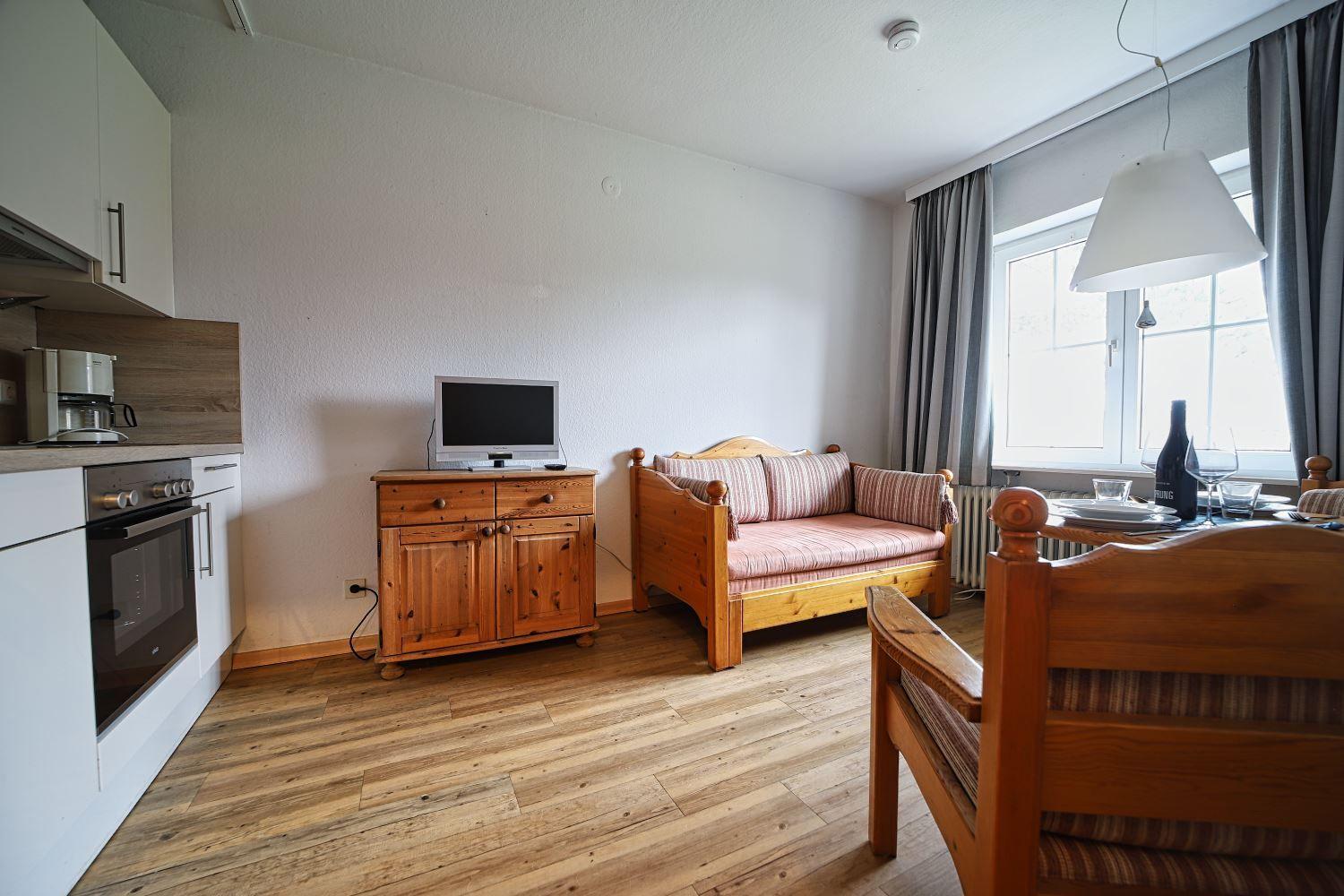 Wohn- und Essbereich mit Holzmöbeln, Fernseher und Küchenzeile.