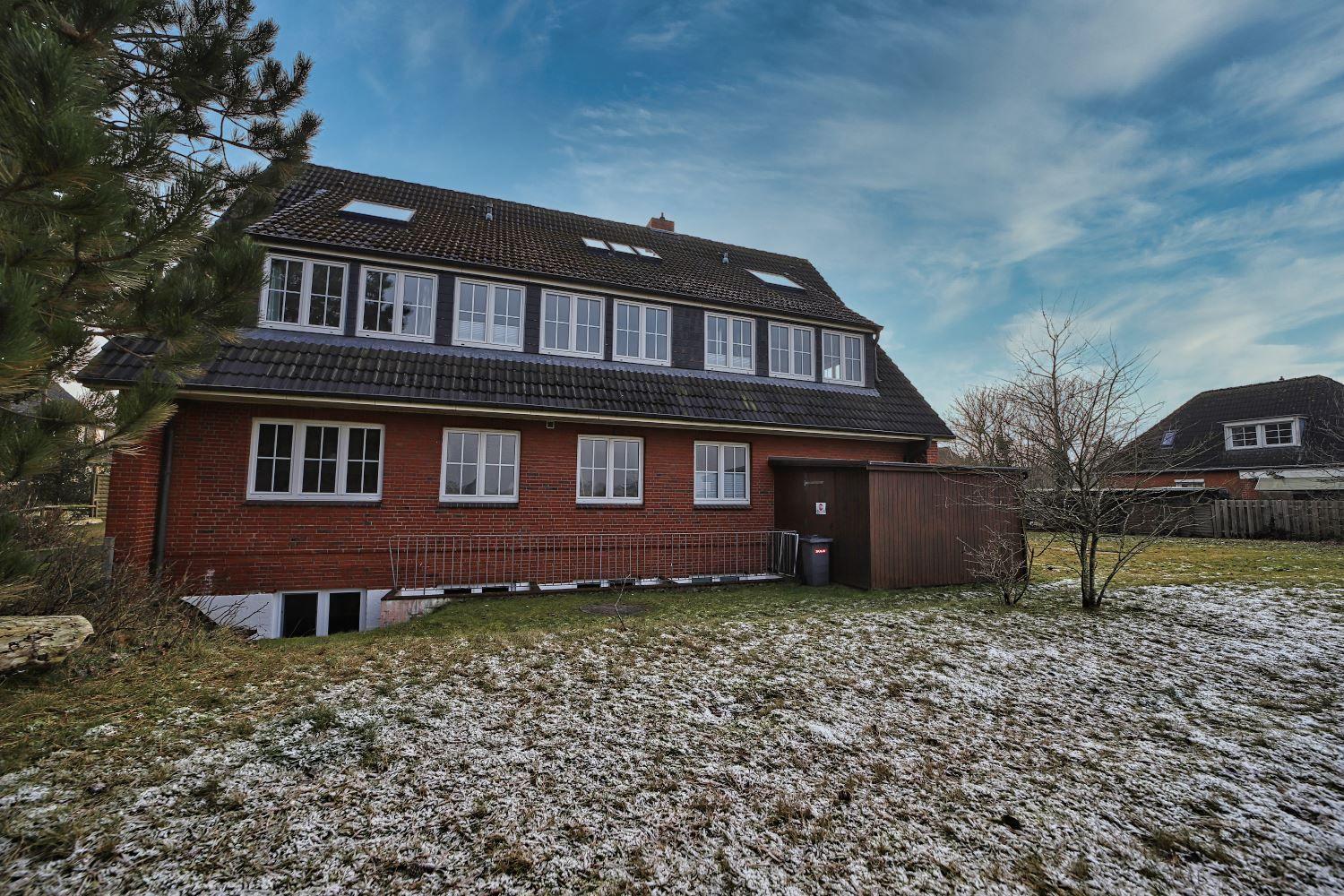 Zweistöckiges Haus mit Schneebedecktem Grundstück und mehreren Fenstern.