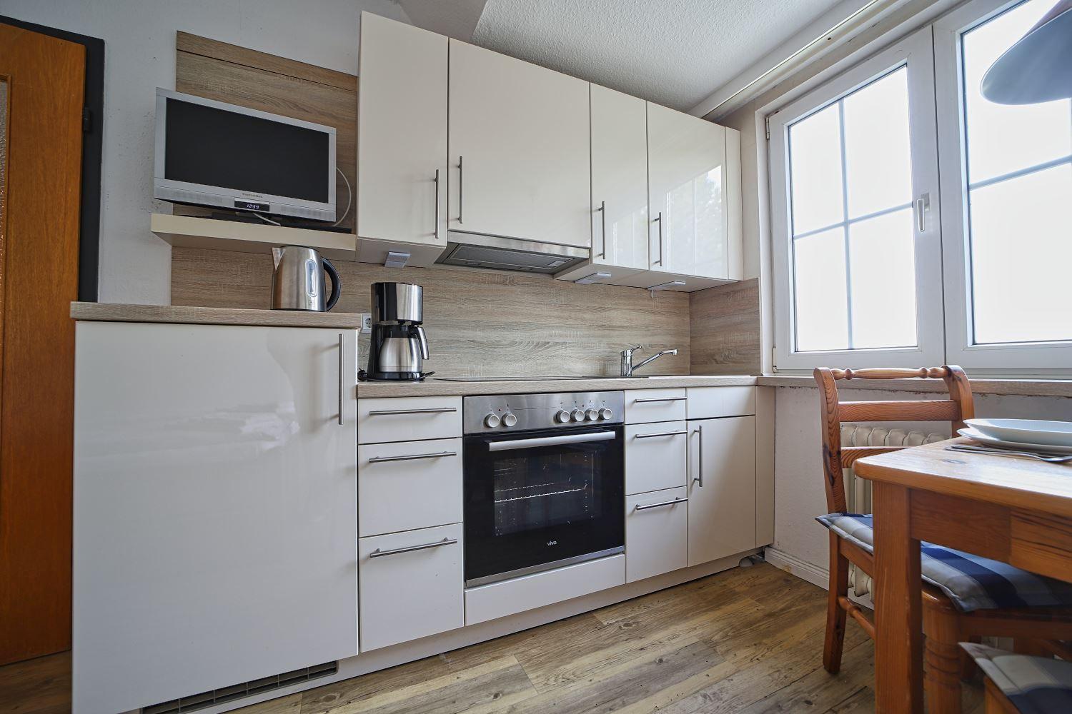 Küche mit weißen Schränken, Herd und Fenster